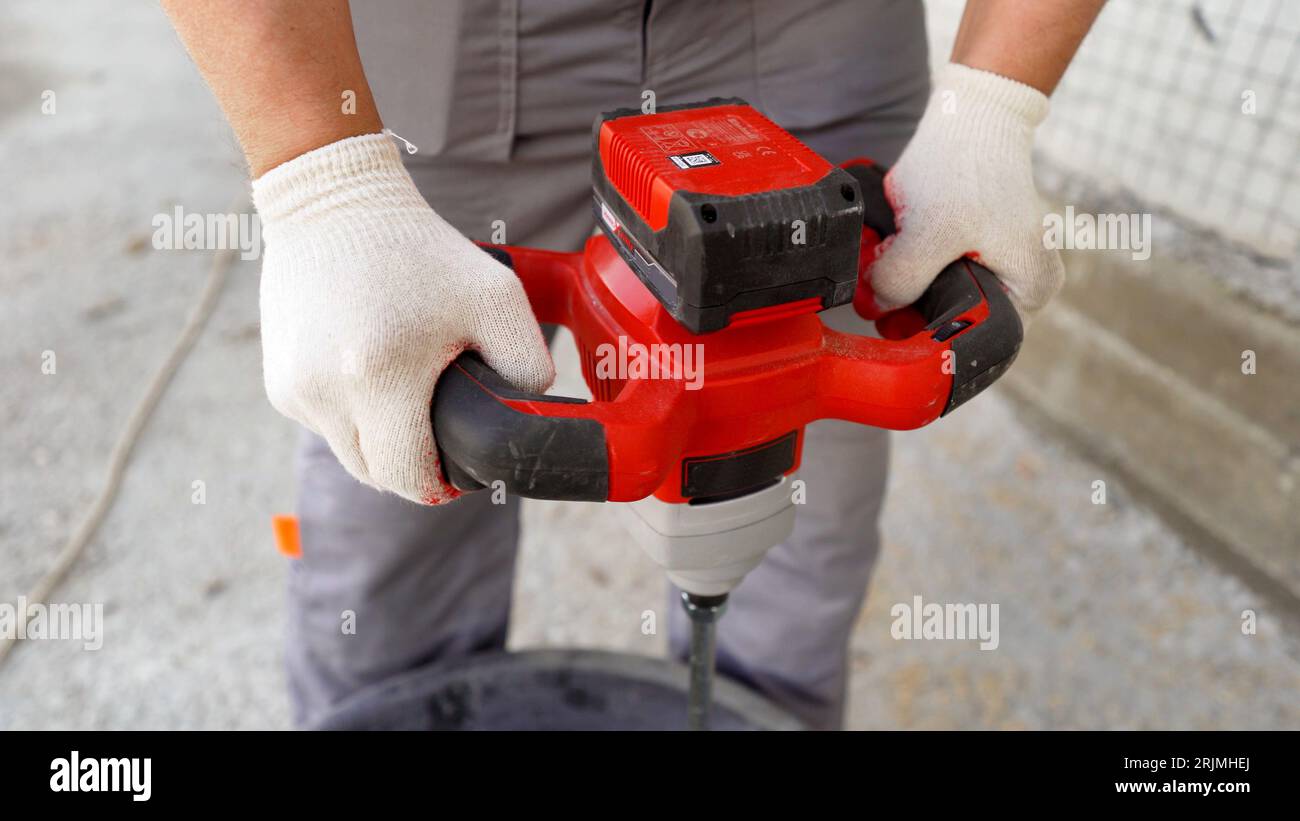 Drilling paddle mixer and black bucket against the wall on the street