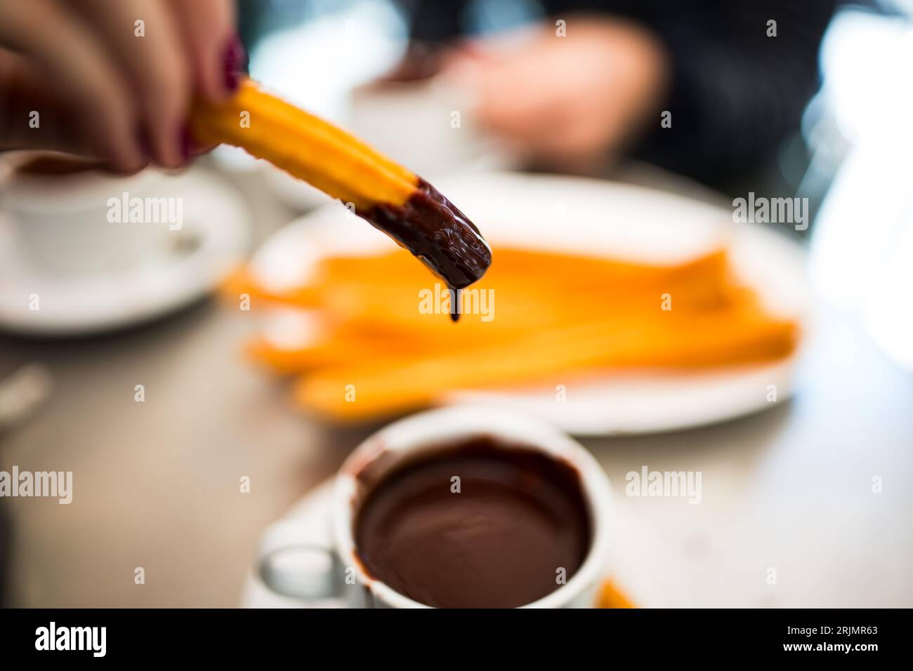 Eating Churros in Madrid, Spain dipped in chocolate, delicatessen, cuisine, fine dining experience, cultural, local food Stock Photo
