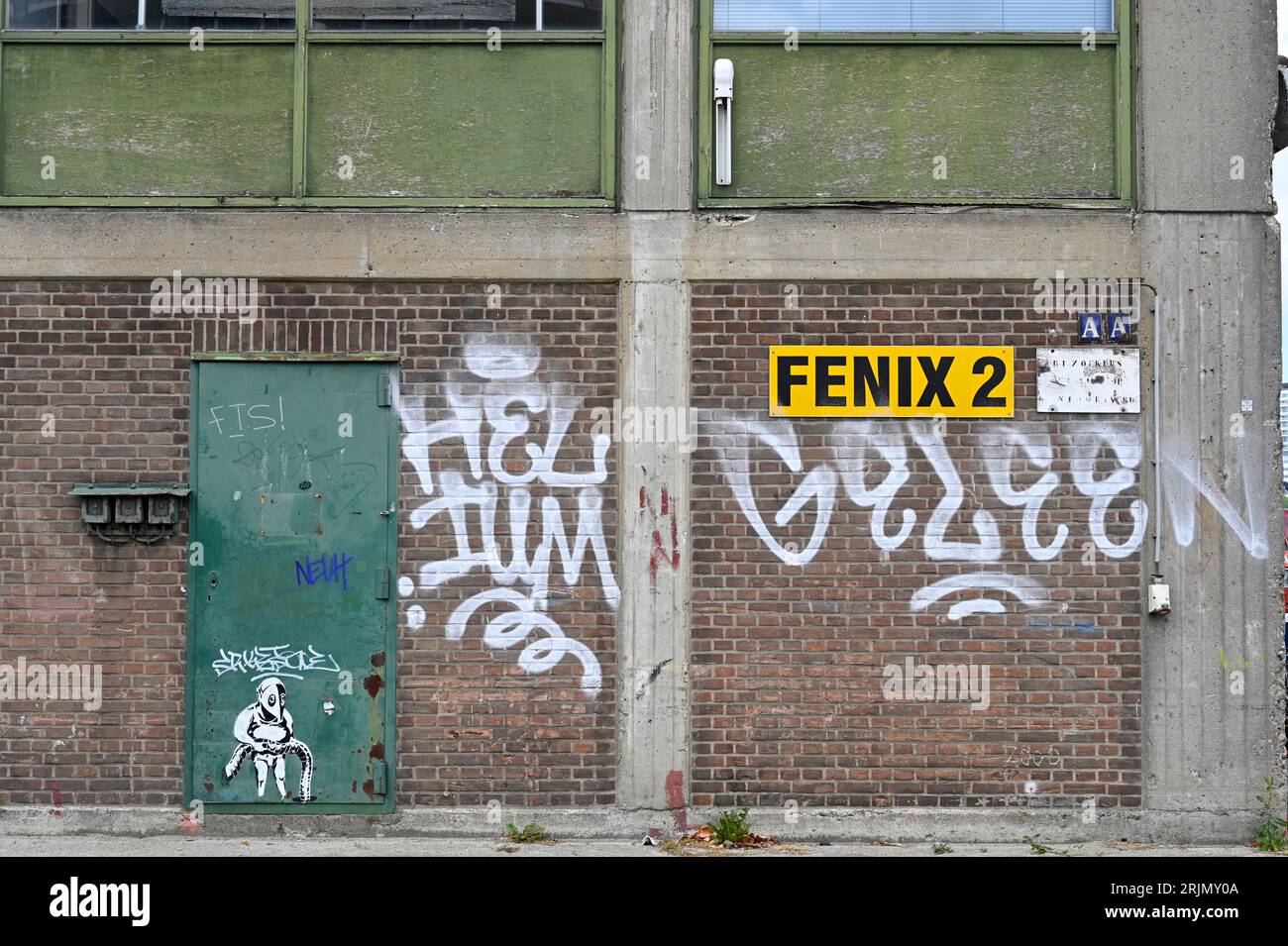 Side wall of the dilapidated Fenix shed 2 with weathered green steel door and white graffiti text and sign; Katendrecht, Rotterdam Stock Photo