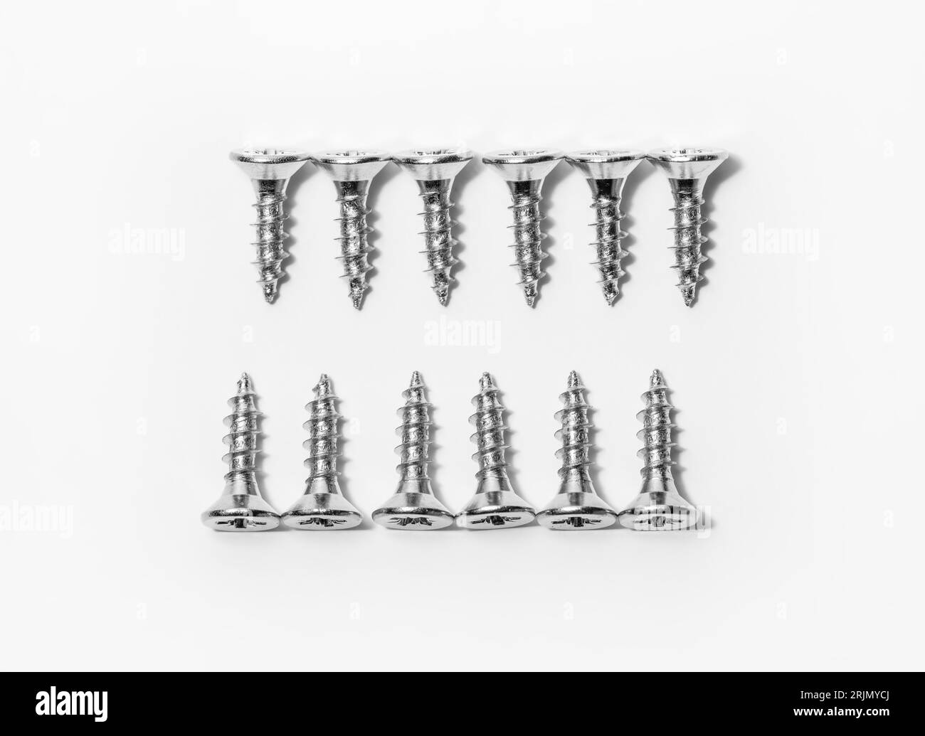 Set of screws on a white background banner with space for text. Construction tools, self-tapping screws for fastening. Black screw hardware. Stock Photo