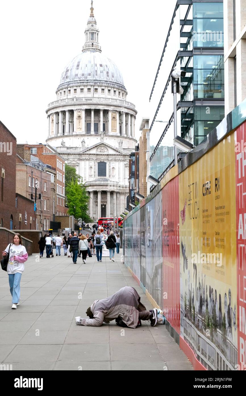 Homeless man begging on street kneeling down on pavement near St Pauls Cathedral in the City of London, England UK Great Britain 2023 KATHY DEWITT Stock Photo