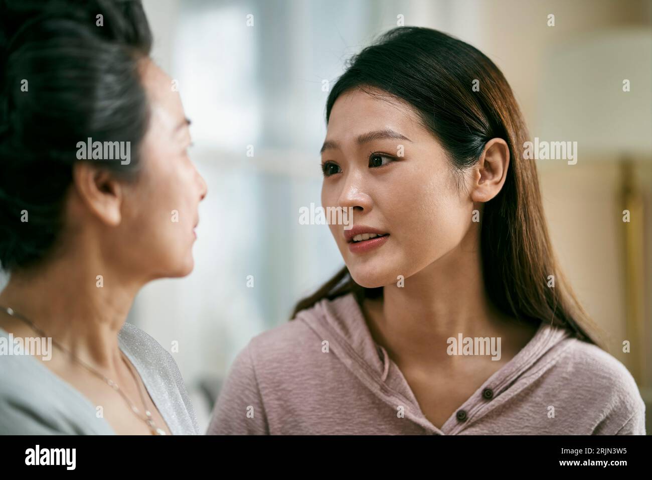 young asian adult daughter consoling senior mother living with mental illness Stock Photo