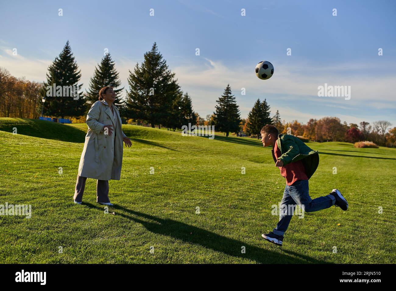 head kick ball, african american boy playing football with happy mother
