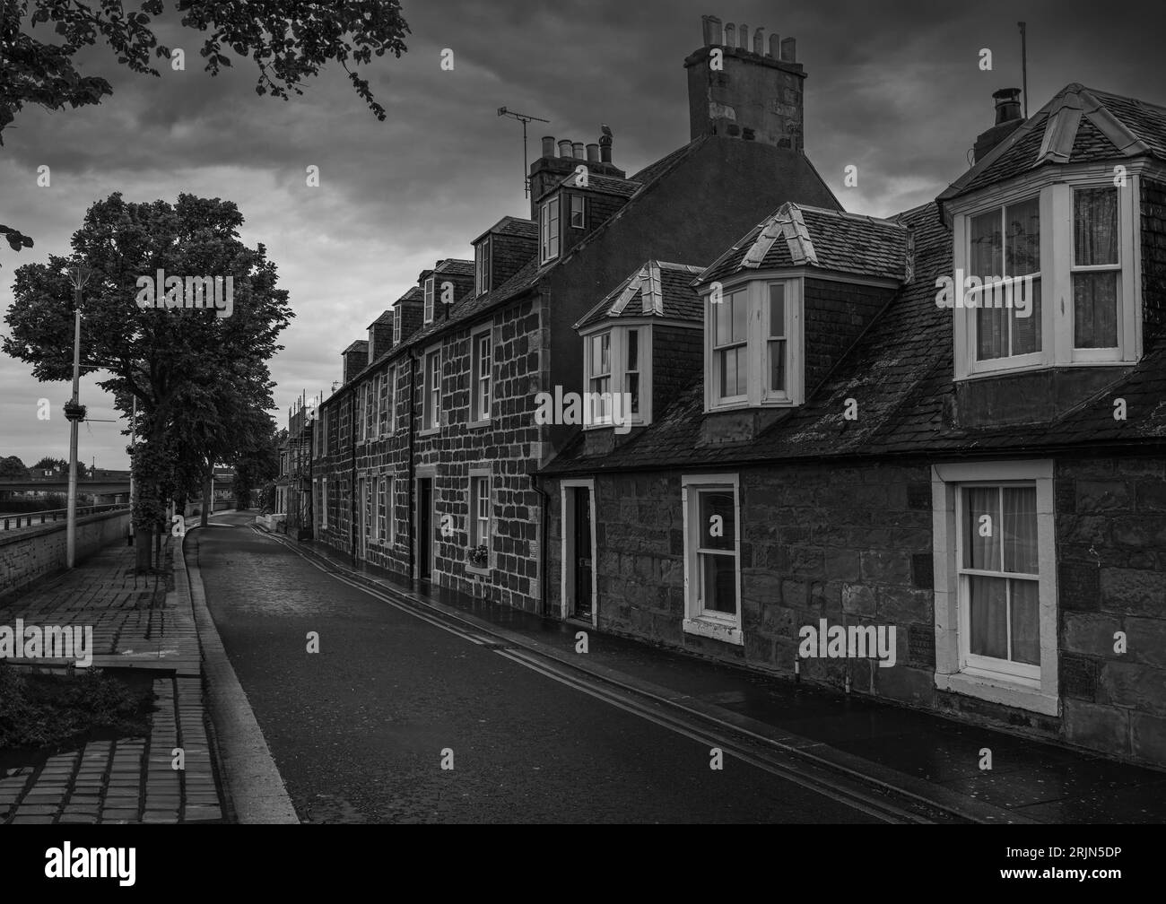 A row of 2 story old houses with a clear street and cloudy sky in