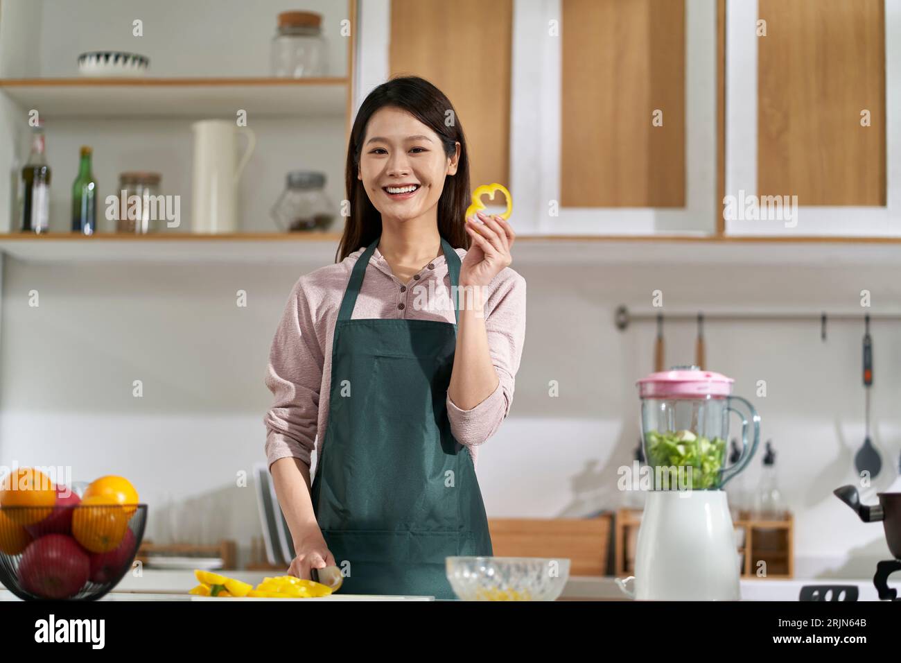 happy young asian woman housewife standing in kitchen looking at camera smiling Stock Photo