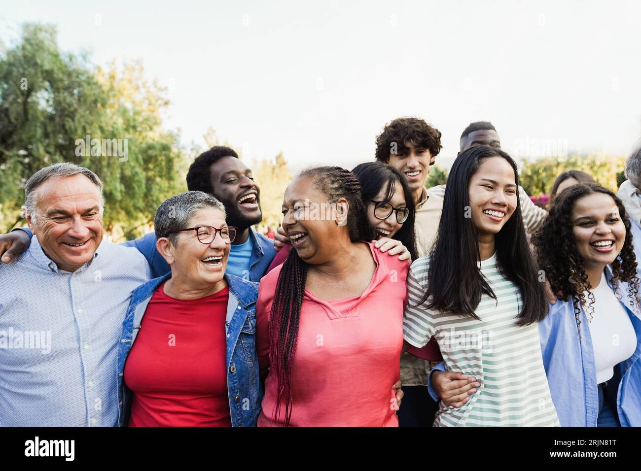 Group of multigenerational people smiling and laughing outdoor - Multiracial friends of different ages having fun together - Main focus on senor women Stock Photo