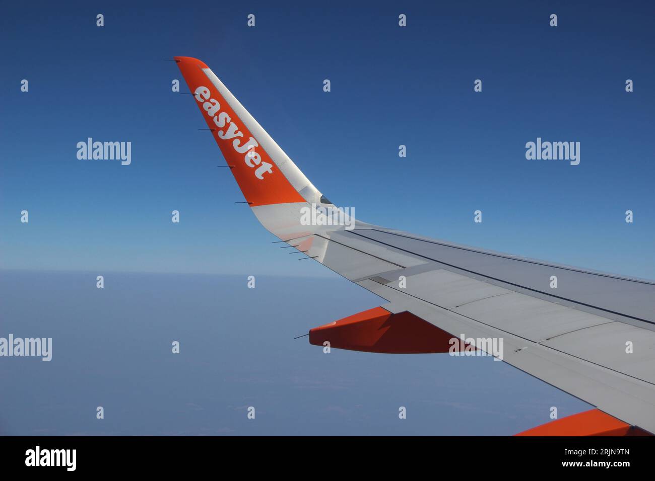 The winglet of an Easyjet airplane against the background of a blue sky. Stock Photo