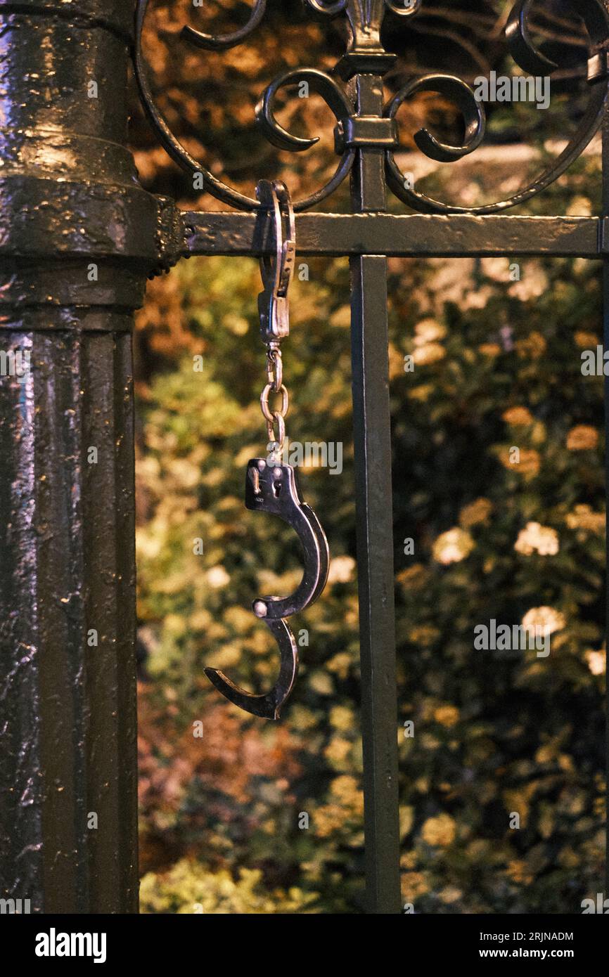 A close-up of handcuffs hanging from a gorgeous iron gate Stock Photo