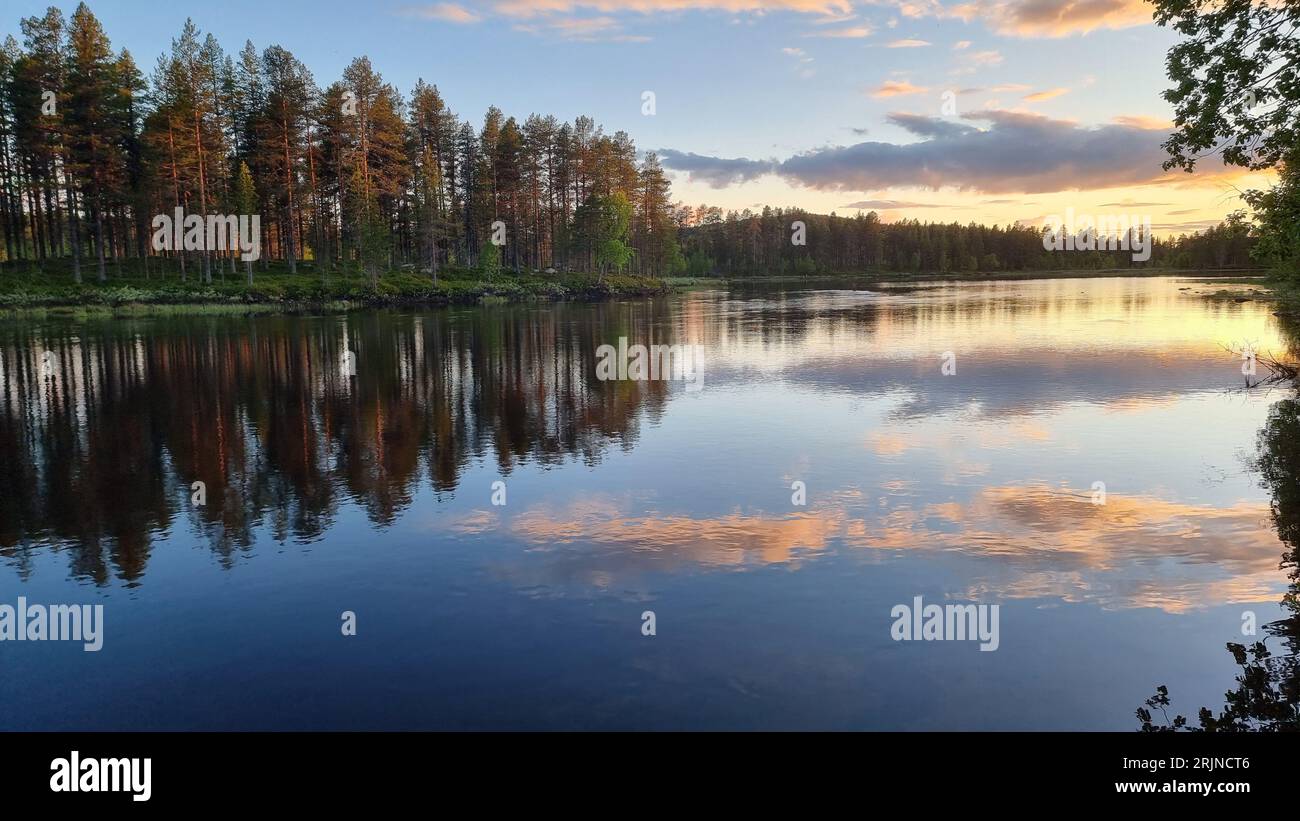 A beautiful landscape of Arvidsjaur, Sweden features a tranquil body of water surrounded by lush trees Stock Photo