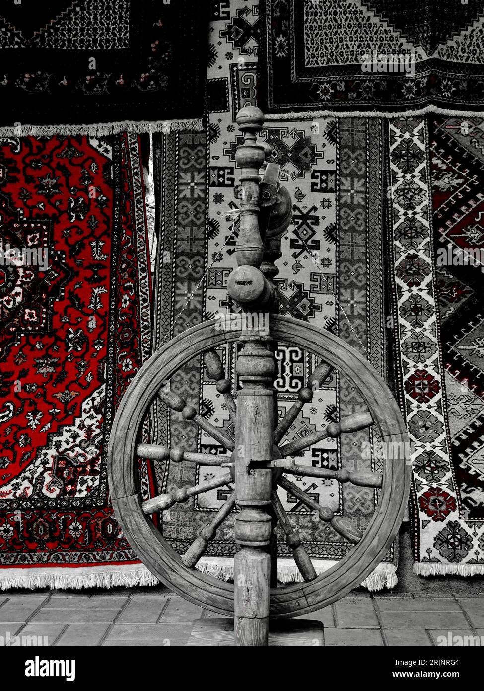 A vintage wooden spinning wheel in front of vibrant carpets Stock Photo Alamy