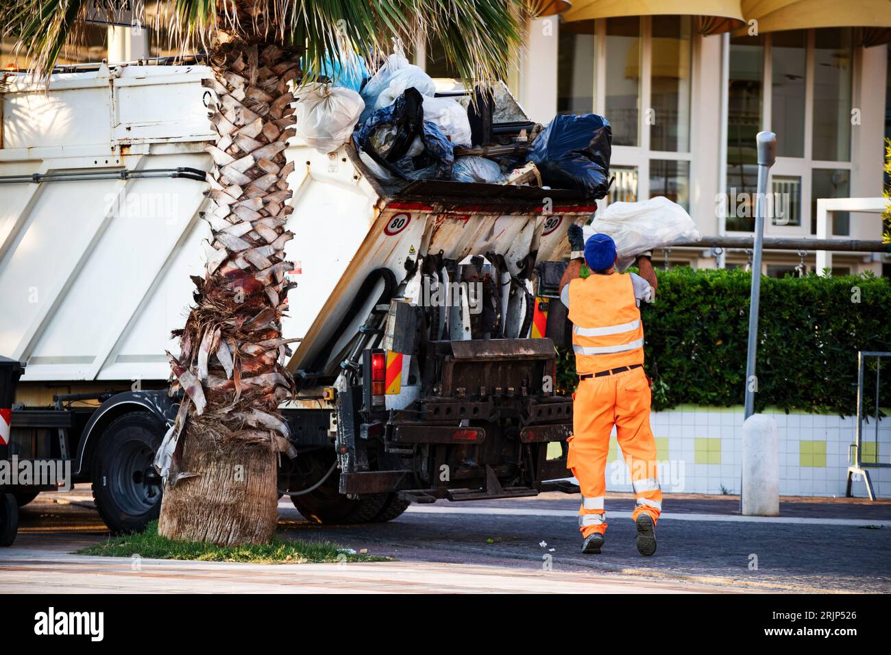 garbage collector loads garbage on the truck Stock Photo