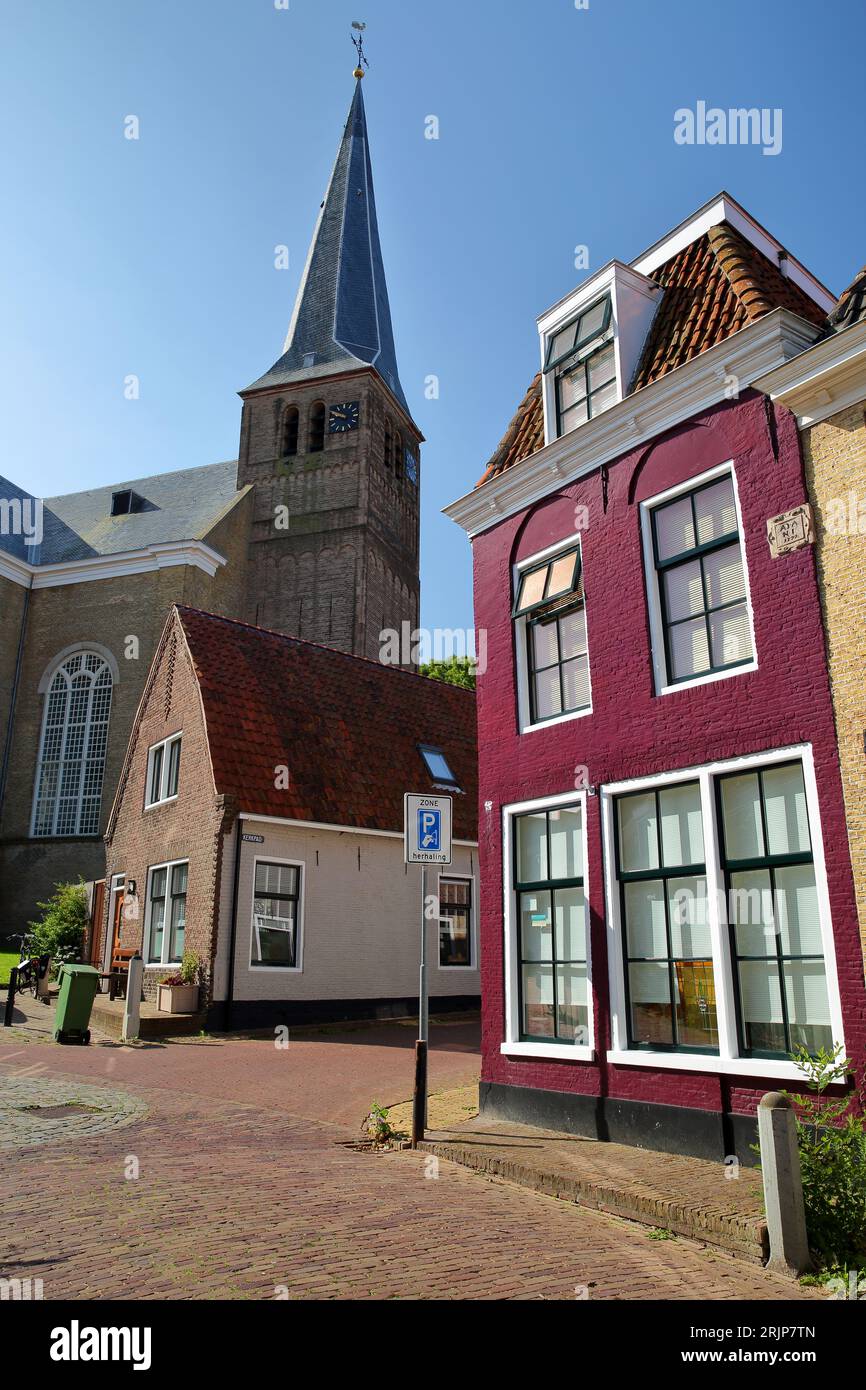 Grote Kerk church viewed from Grote Kerkstraat street in Harlingen, Friesland, Netherlands, with colorful historic buildings in the foreground Stock Photo