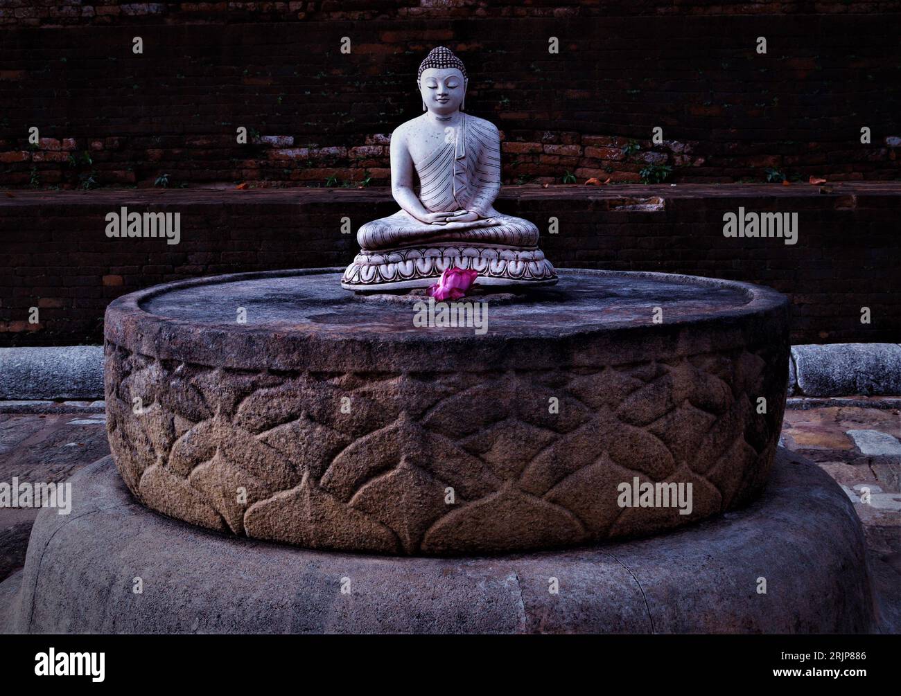 A closeup of the Buddha statue seated on a stone pedestal in lotus ...