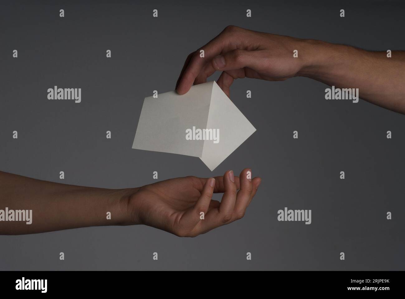 Photography of a hand giving a paper to other had with gray background Stock Photo