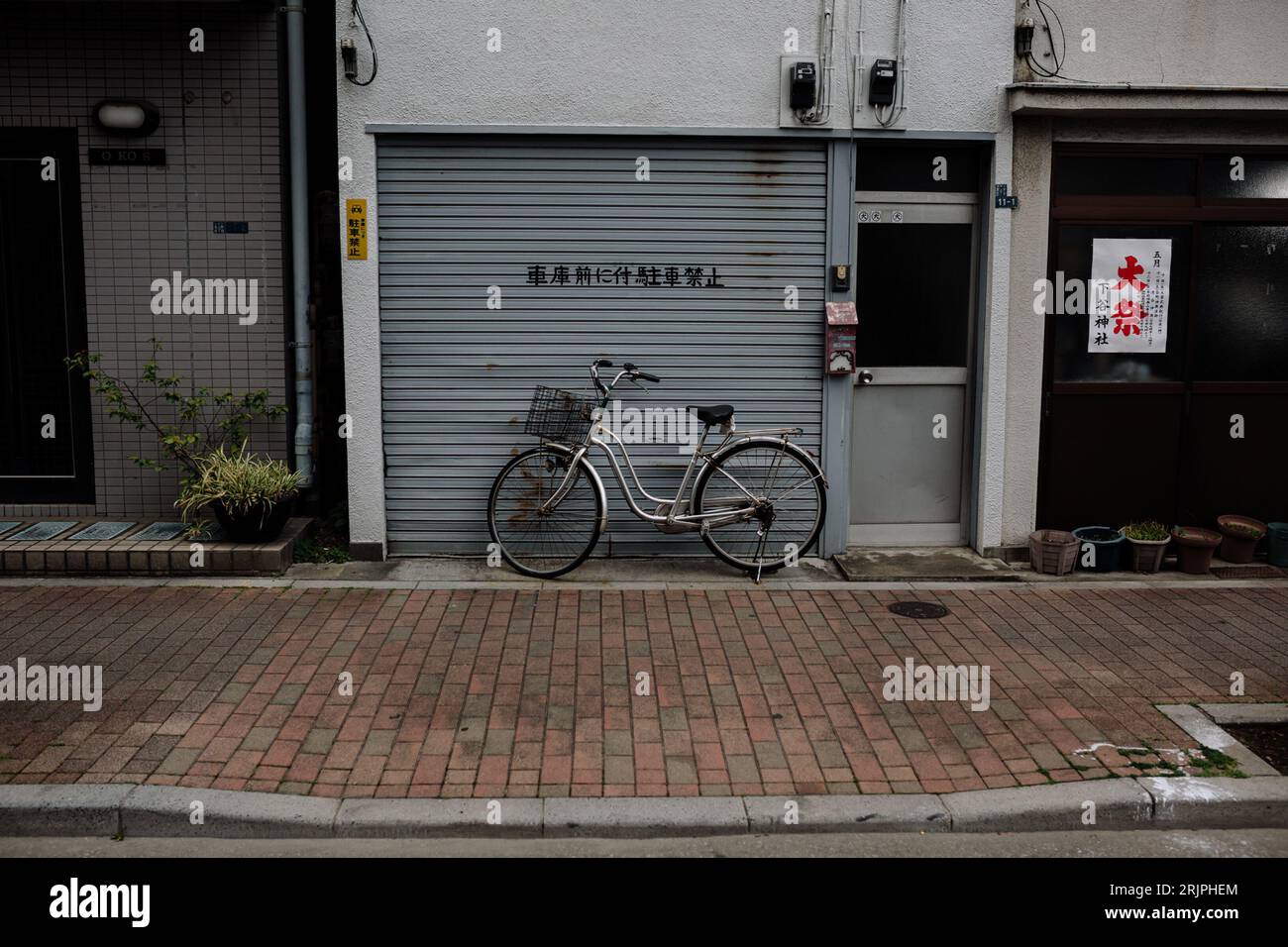 A horizontally oriented image of an abandoned store with a bicycle parked in front of the entrance in Tokyo, Japan Stock Photo