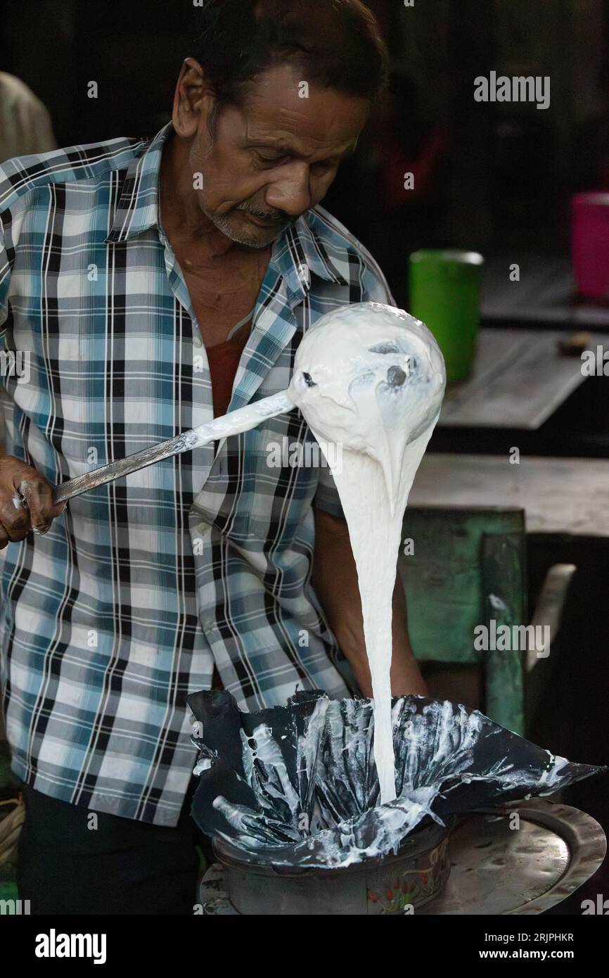 Man pouring jalebi batter into a bag from which he will pipe into hot fat for frying. Silghat, Assam, India. Stock Photo