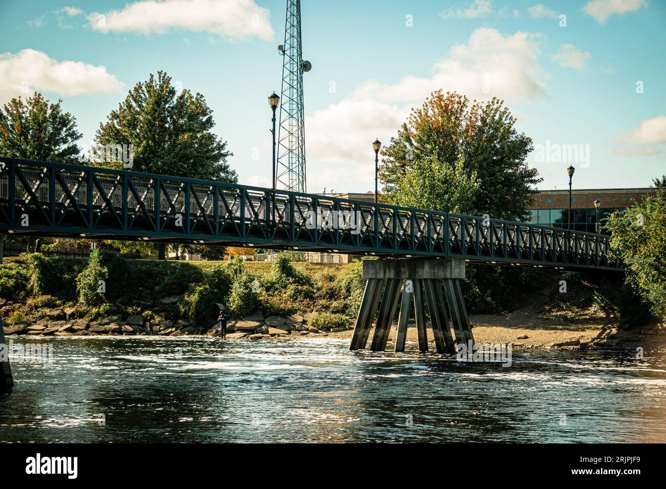 A scenic view of a metallic suspension bridge over a river on a sunny day Stock Photo