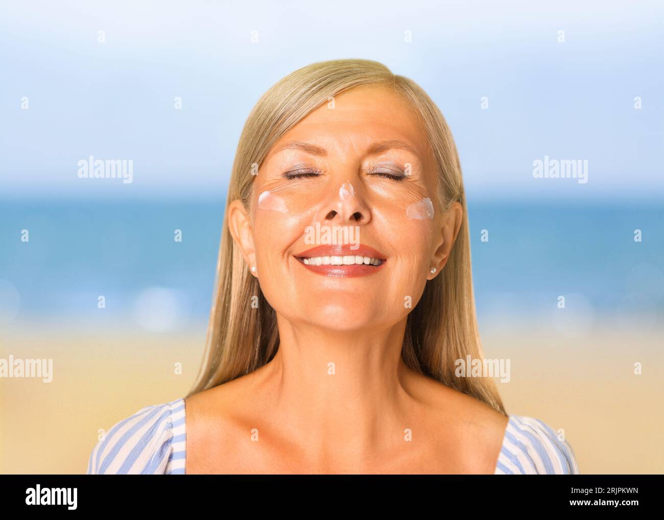 Sun protection. Beautiful young woman with sunblock on her face near sea Stock Photo