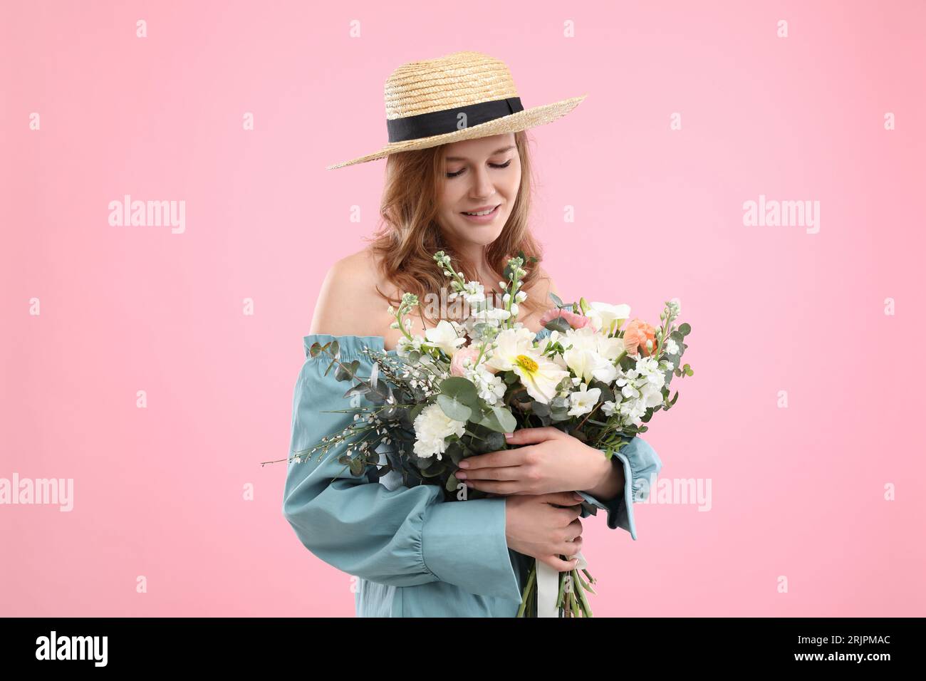 Beautiful woman in straw hat with bouquet of flowers on pink background ...