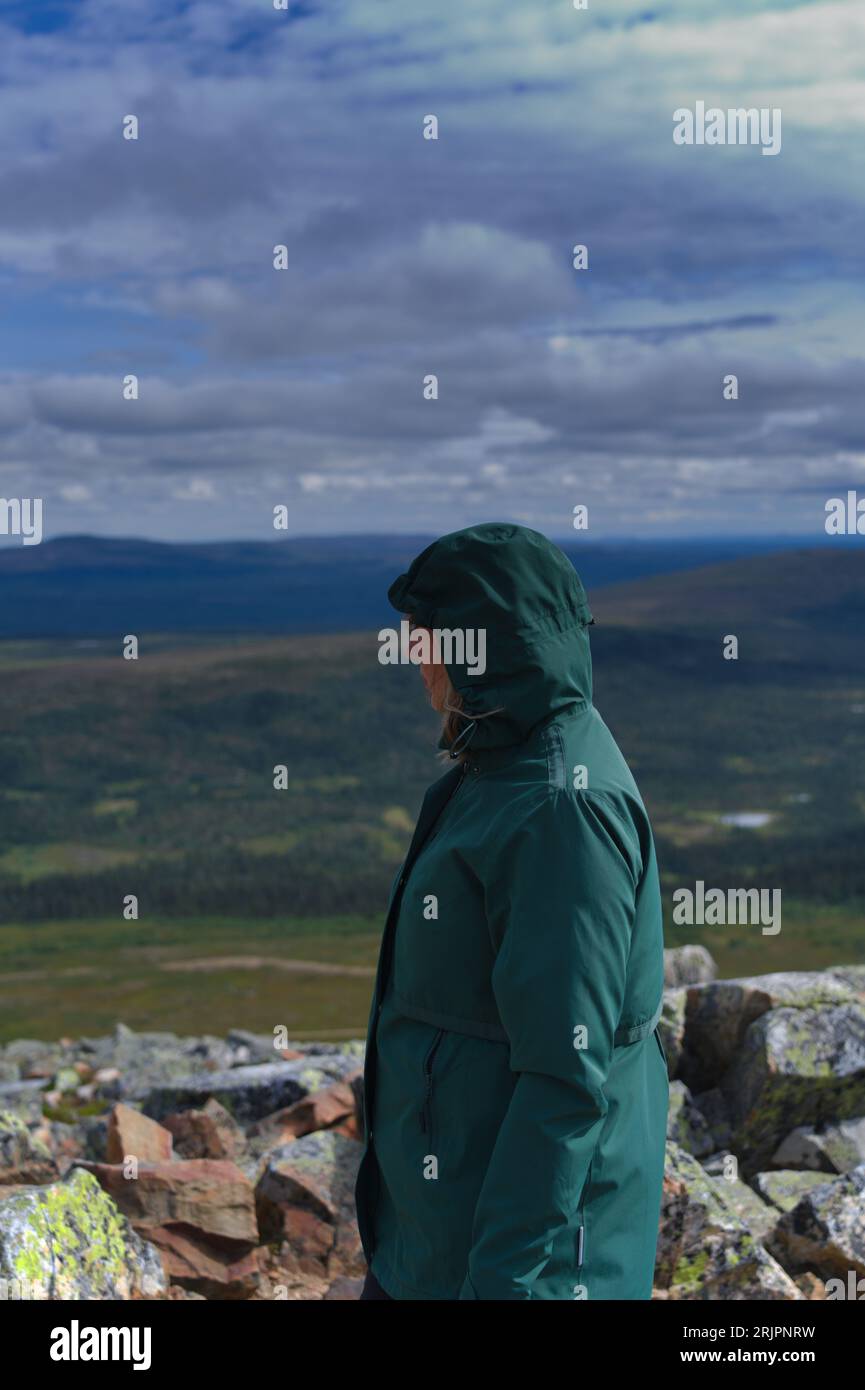 Side view of active solo female hiker enjoying the view on top of Nipfjället mountain in Idre alone on a cloudy day in Swedish nature landscape Stock Photo