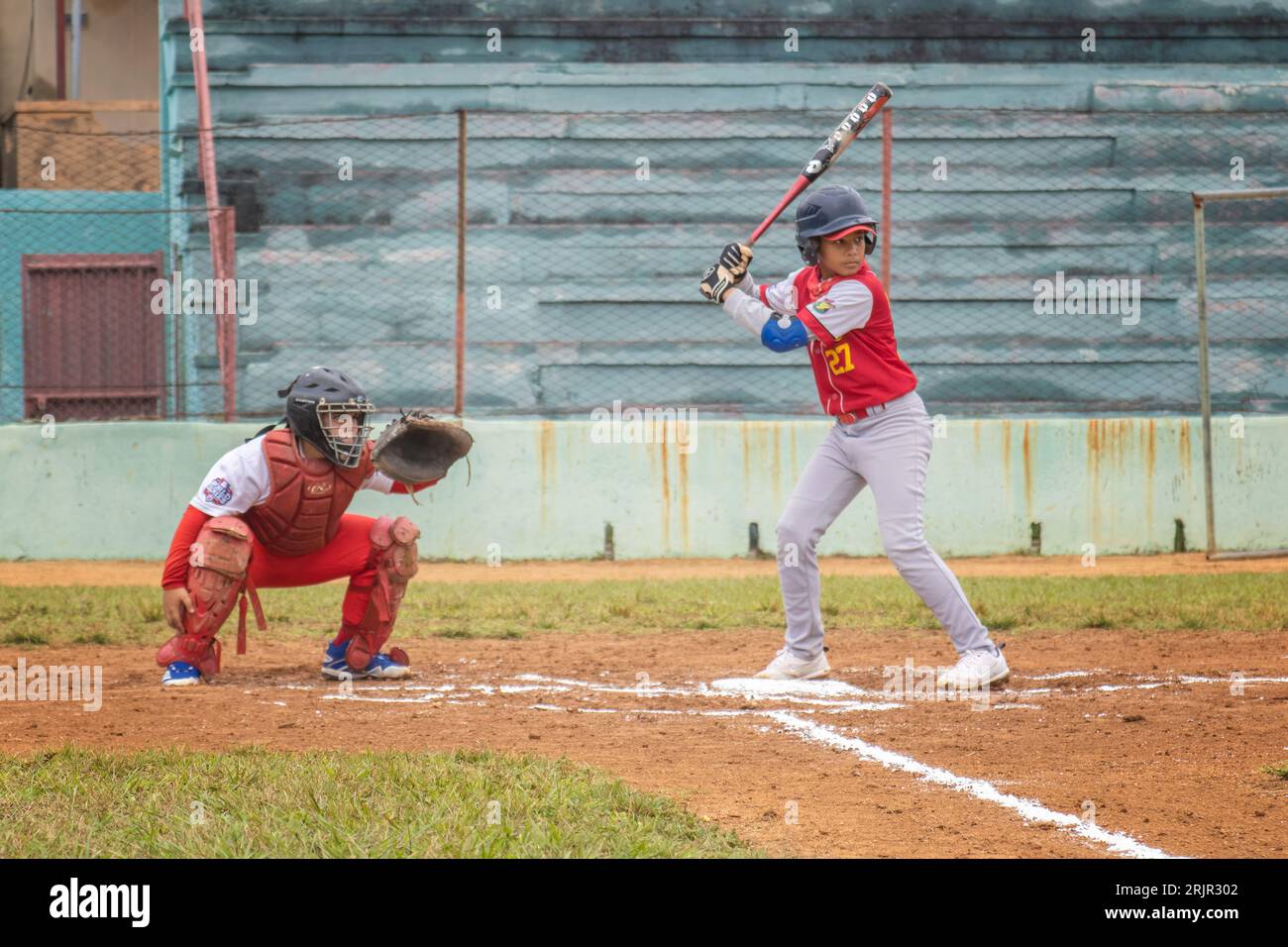 A young boy in a baseball uniform stands ready to hit a ball at a