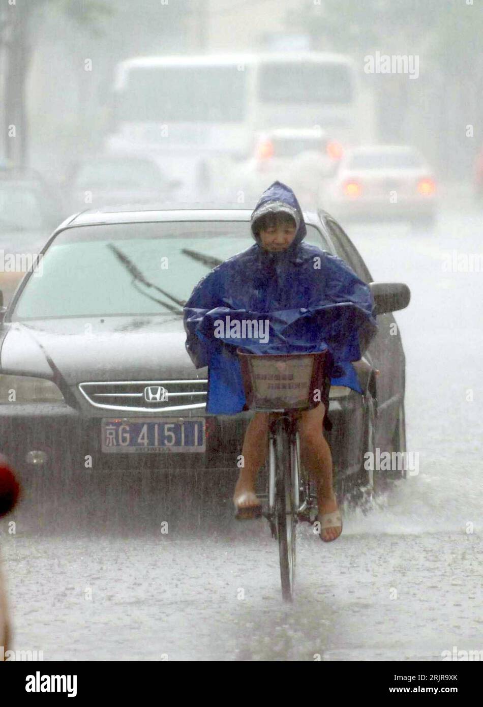 Bildnummer: 51349484  Datum: 24.07.2006  Copyright: imago/Xinhua Radfahrerin kämpft sich durch einen heftigen Regenguss in Peking - PUBLICATIONxNOTxINxCHN, Personen; 2006, Peking, Regenfall, Regenfälle, Regen, Regenwetter, Wasser, Unwetter, Radfahrer, regnen, regnet; , hoch, Kbdig, Einzelbild, China,  , Straße, Verkehr, Wetter Stock Photo
