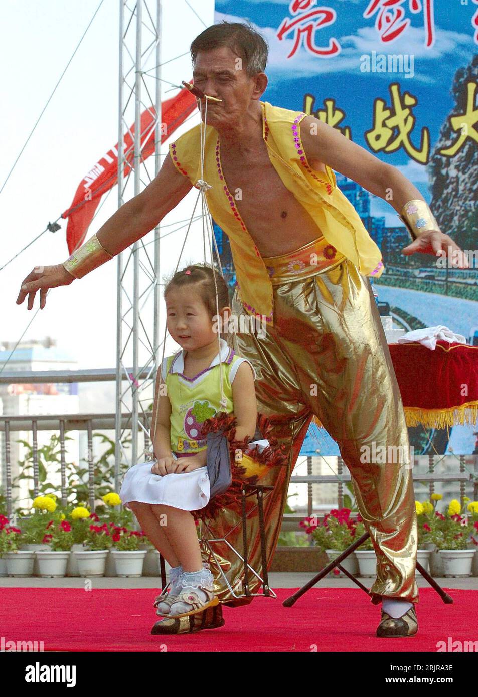 Bildnummer: 51350476  Datum: 08.07.2006  Copyright: imago/Xinhua Chinesischer Artist trägt ein Mädchen auf einem Stuhl nur mit dem Mund bei eine Wettbewerb in Ürümqui in Xinjiang - PUBLICATIONxNOTxINxCHN, Personen , Anstrengung , kurios; 2006, Urumqui, Xinjiang, Mann, Männer, Chinese, Chinesin, Chinesen, Artist, Artistik, Akrobat, Akrobatik, Kind, Kinder, heben, anheben, hebt an, hebend, Wettbewerbe, Wettkampf, Wettkämpfe,; , hoch, Kbdig, Einzelbild, Zirkuskünste, Kunst, China Stock Photo