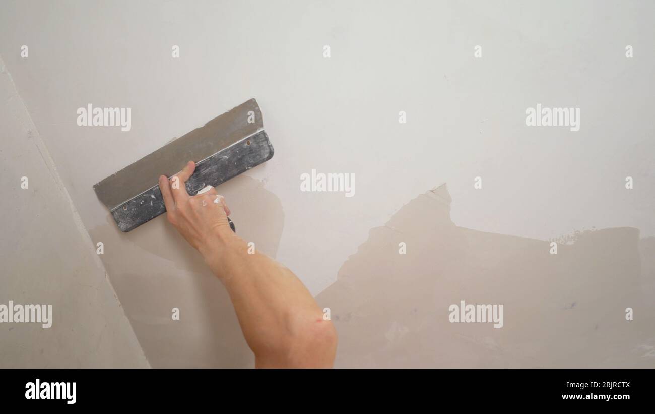 Sanding the ceiling before painting. A worker cleans the ceiling with a