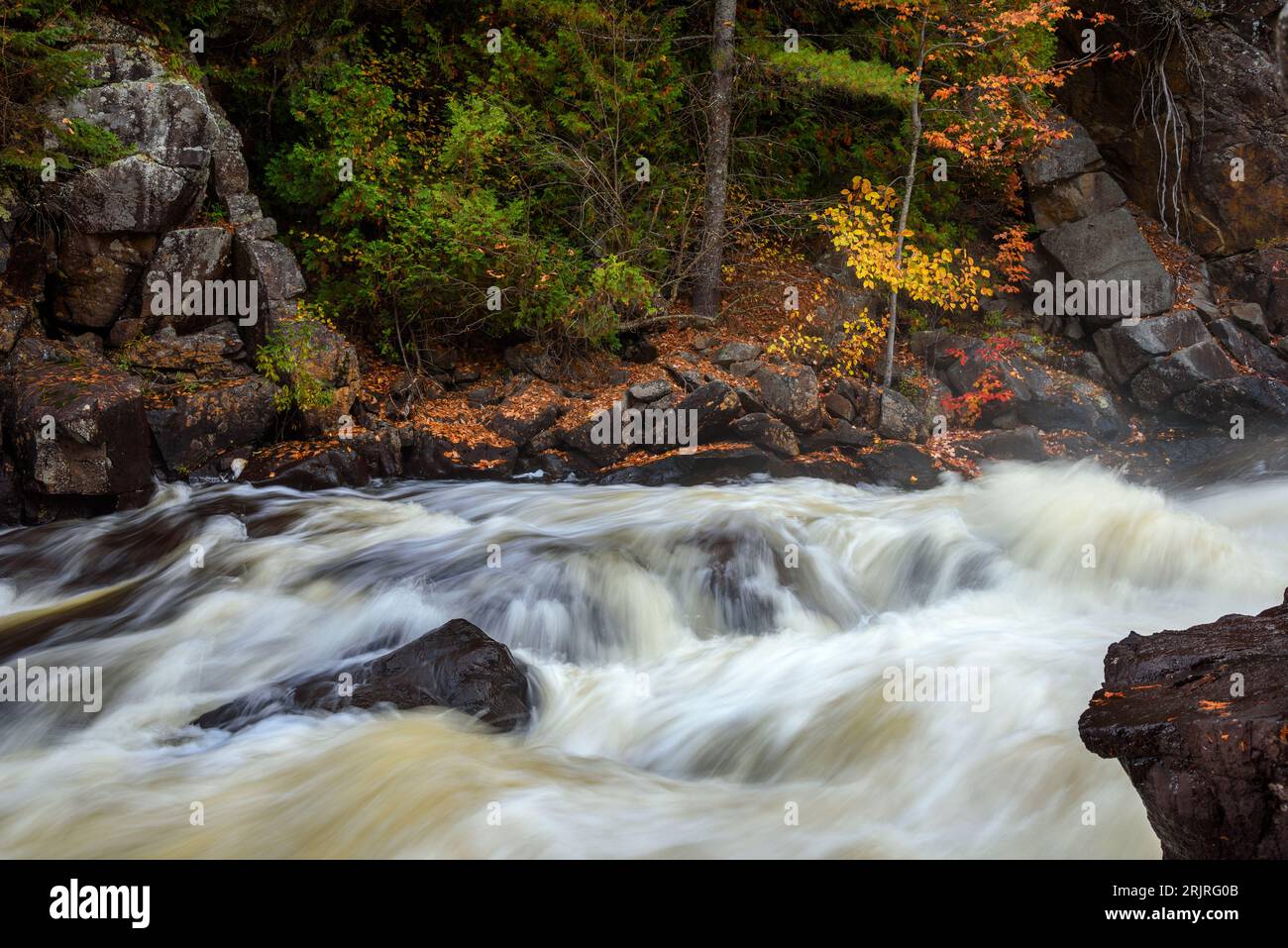 Fast flowing water near a waterfall along a mountain river in autumn Stock Photo