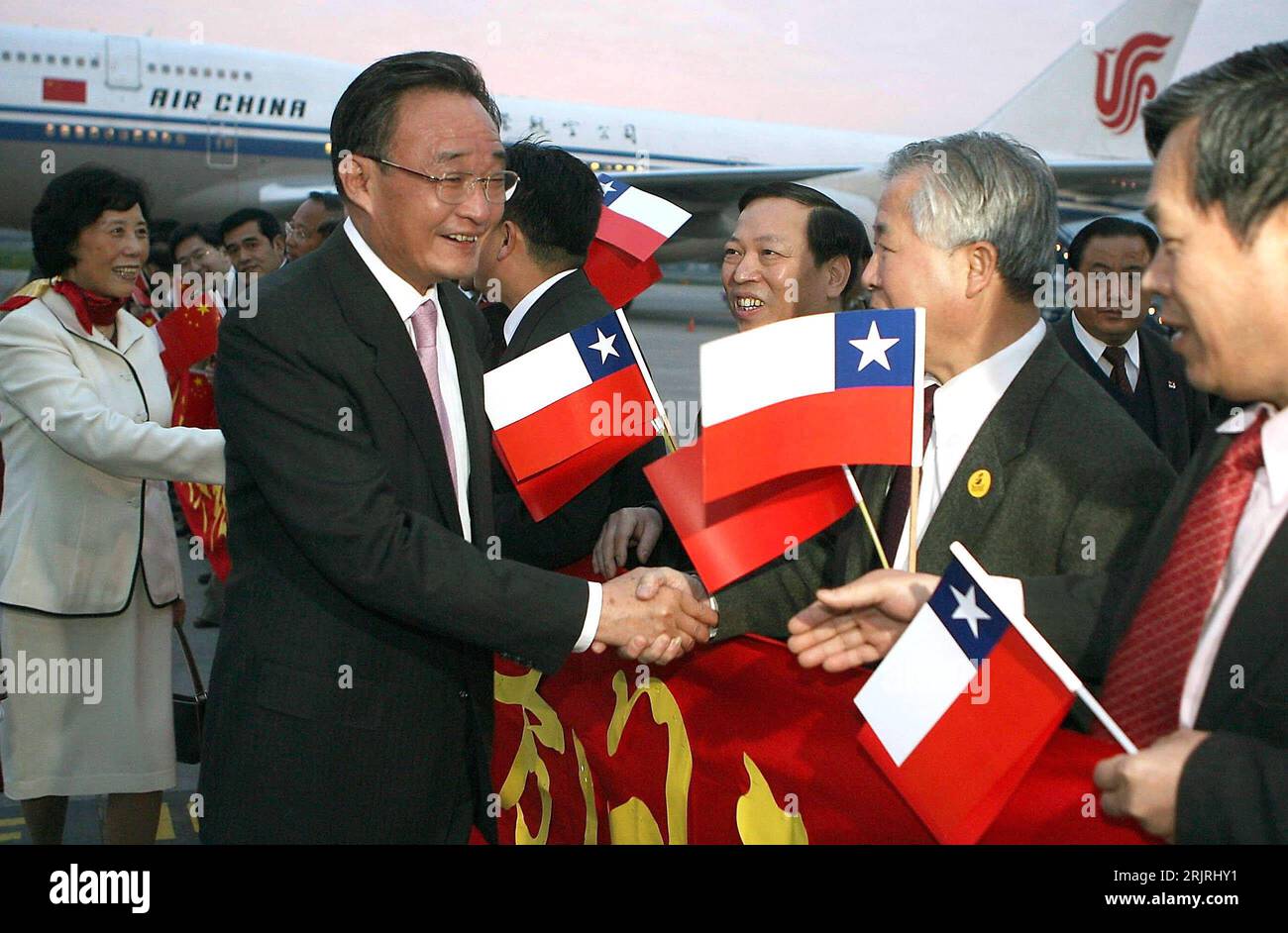 Bildnummer: 51430787  Datum: 05.09.2006  Copyright: imago/Xinhua Wu Bangguo (2.v.li., CHN/Stellvertretender Premierminister) mit seiner Ehefrau begrüßt von Chinesen mit chilenischen Nationalfahnen während ihrer Ankunft in Santiago de Chile - PUBLICATIONxNOTxINxCHN, Personen , optimistisch; 2006, Santiago de Chile, Politiker, Politik, Frau, Paar, Ehepaar, chilenisch, chilenische, Fahne, Shakehands, shake hands, Begrüßung, lächeln; , quer, Kbdig, Gruppenbild, close, Chile, Randbild, People Stock Photo