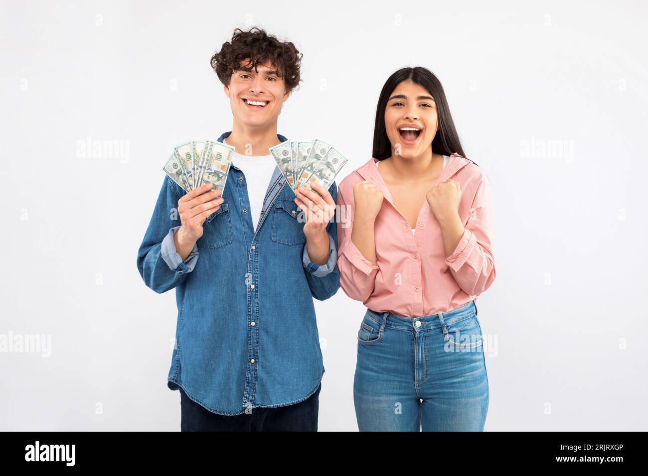 Joyful Young Couple Holding Money Cash Celebrating Financial Luck, Studio Stock Photo