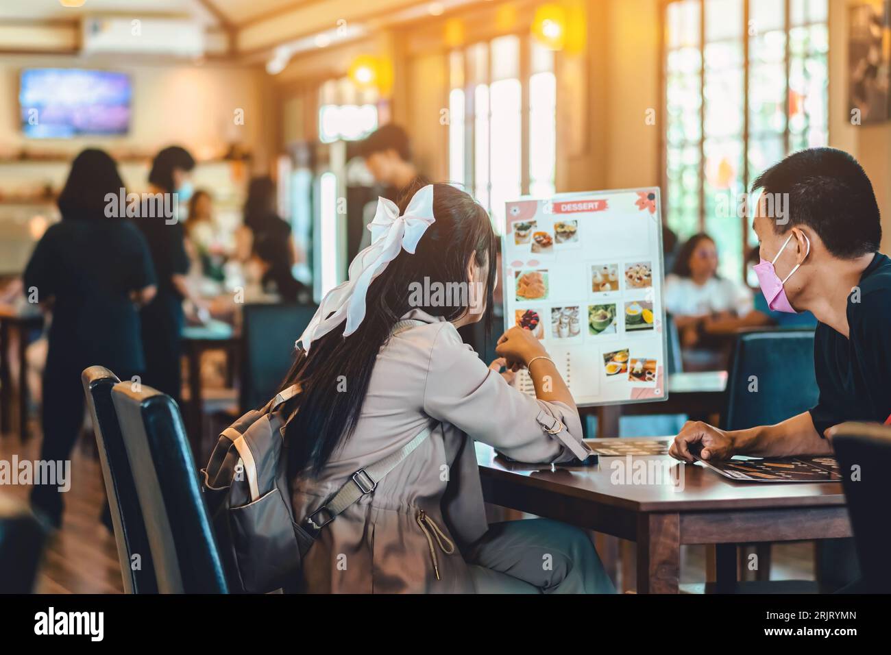 Back view of Asian young couple reading menu and choosing meal together ...