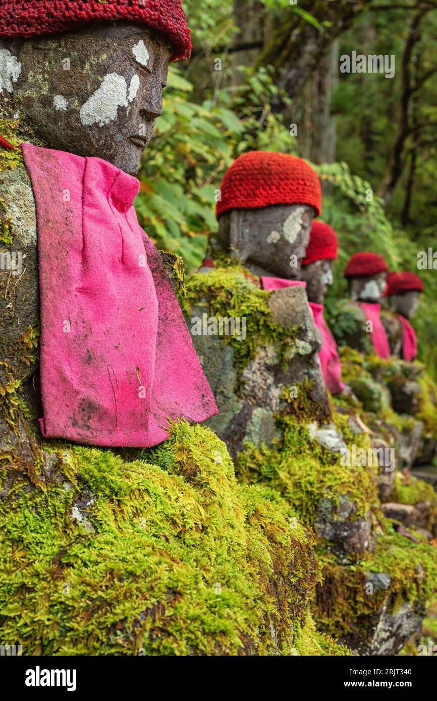 Moss covered Jizo statues, wearing red hats and bibs, at Kanmangafuchi