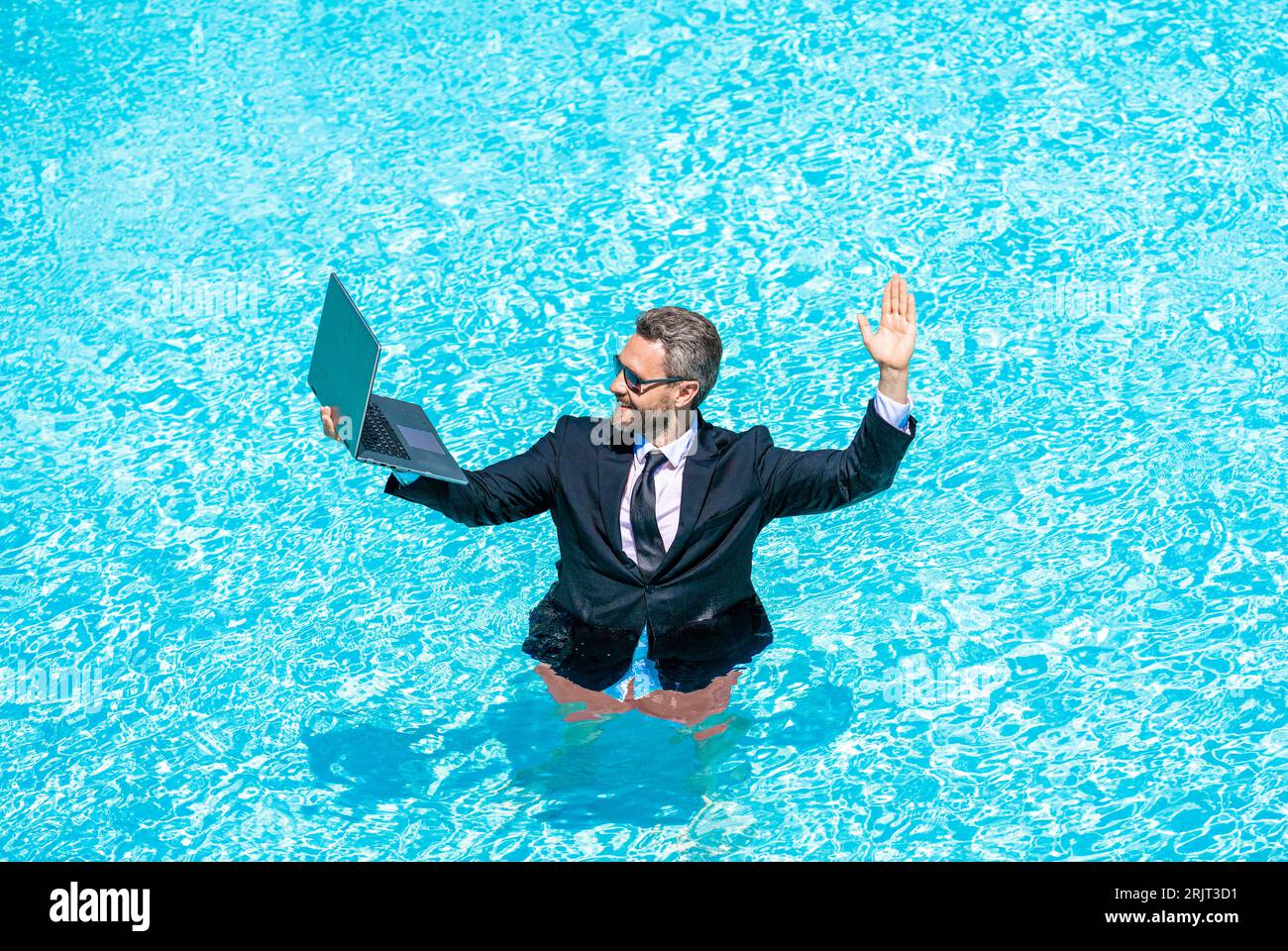 Summer business dreams. successful man. Businessman in suit with laptop in swimming pool. business man on summer vacation. businessman in wet suit in Stock Photo