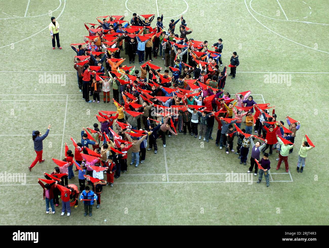 Schüler einer Grundschule bilden die symbolische rote Schleife in der Turnhalle anlässlich des Welt-AIDS-Tages in Hefei - PUBLICATIONxNOTxINxCHN Stock Photo