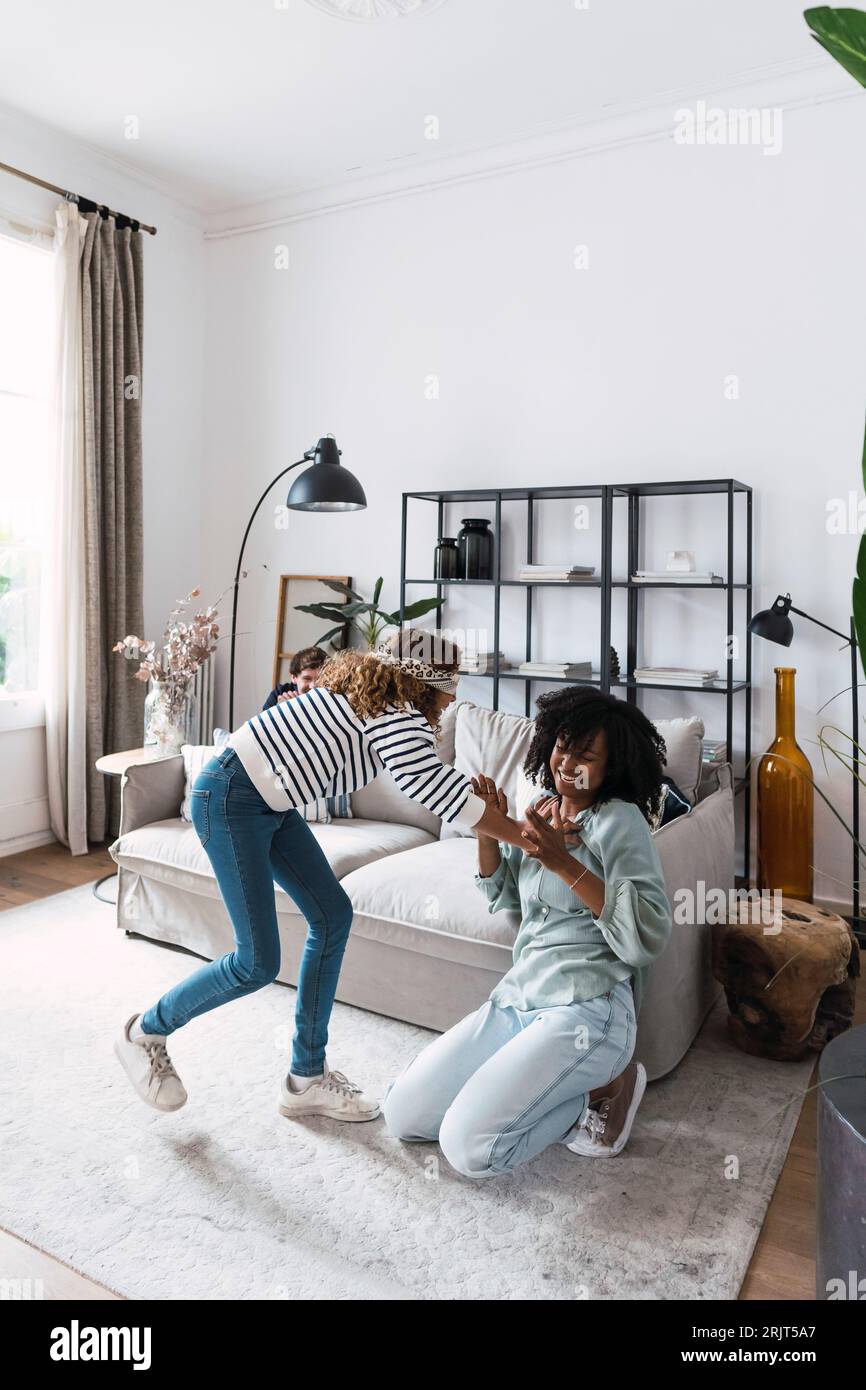 Daughter catching mother playing blind man's buff with her parents in the living room Stock Photo