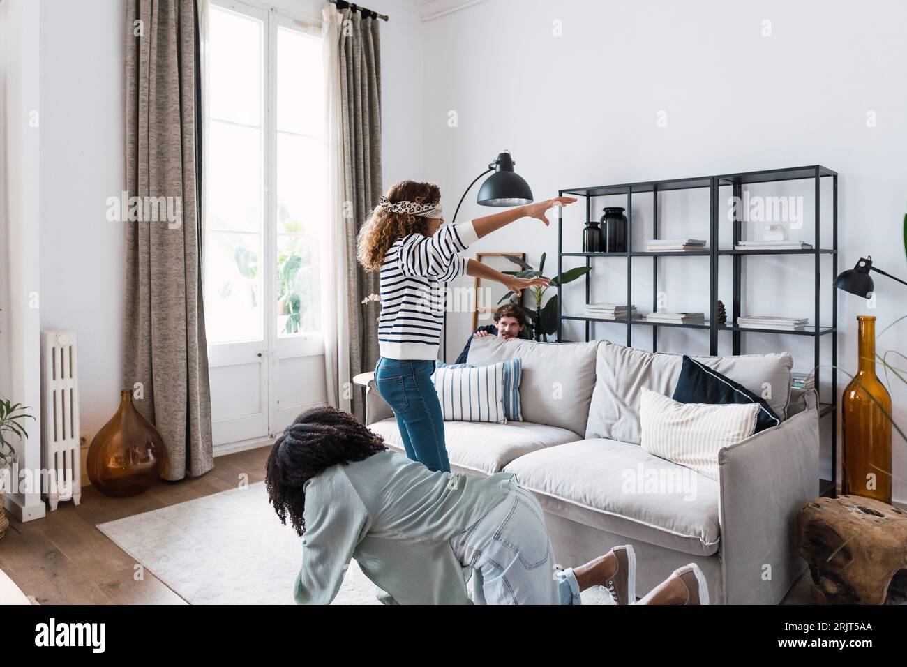Happy parents playing blind man's buff with their daughter in the living room Stock Photo
