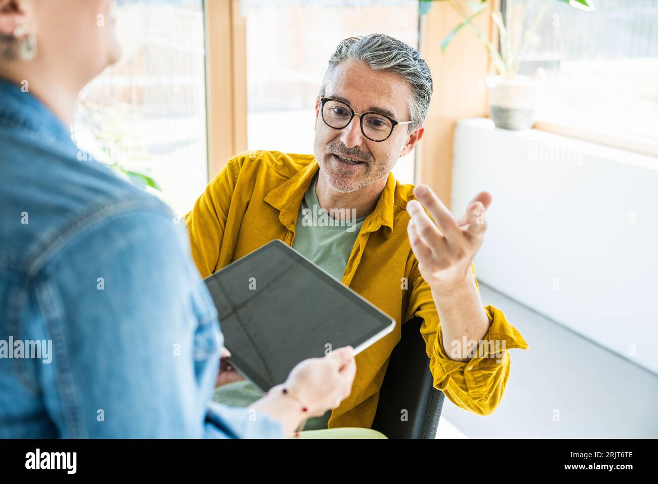 Smiling businessman having discussion with businesswoman over tablet PC Stock Photo