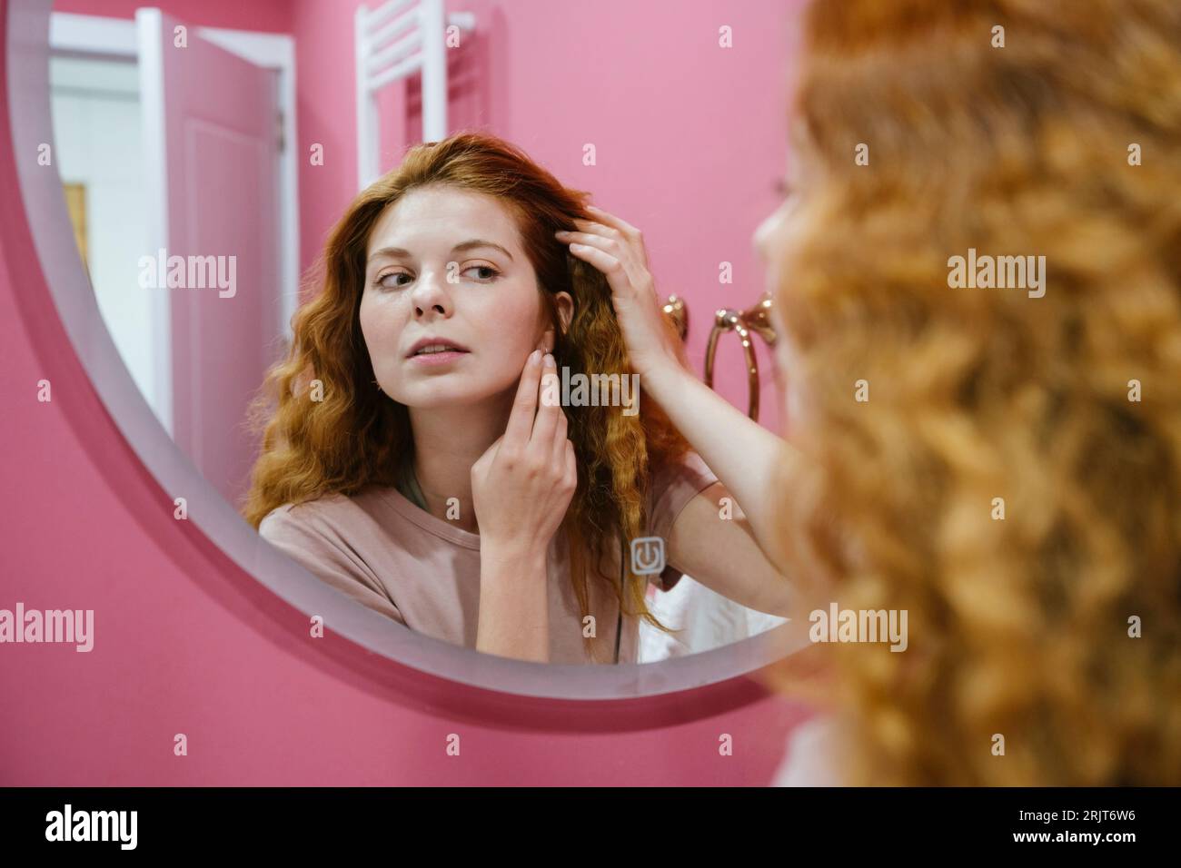 Reflection of redhead woman in bathroom mirror Stock Photo