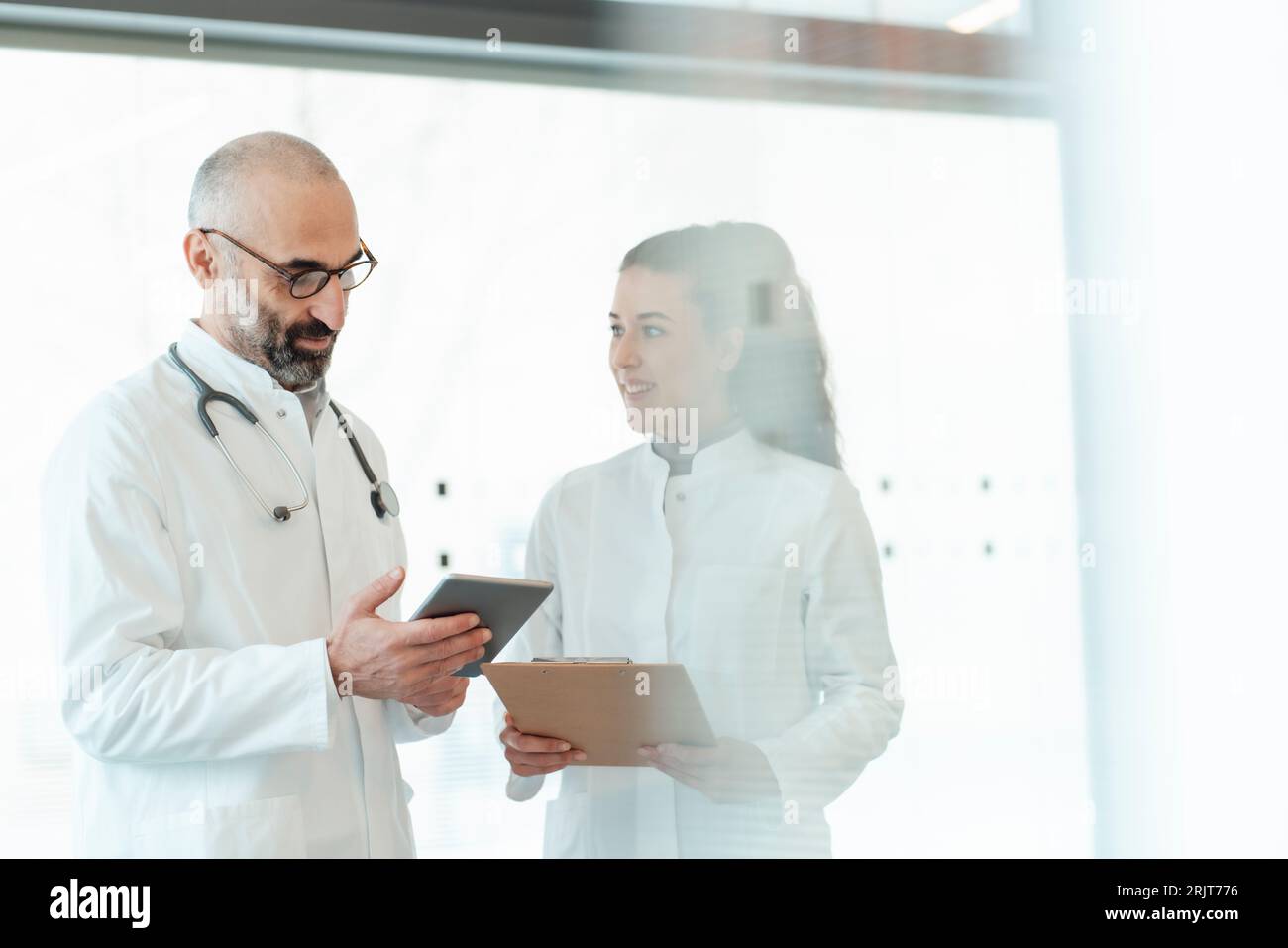 Happy doctor with colleague using tablet PC Stock Photo