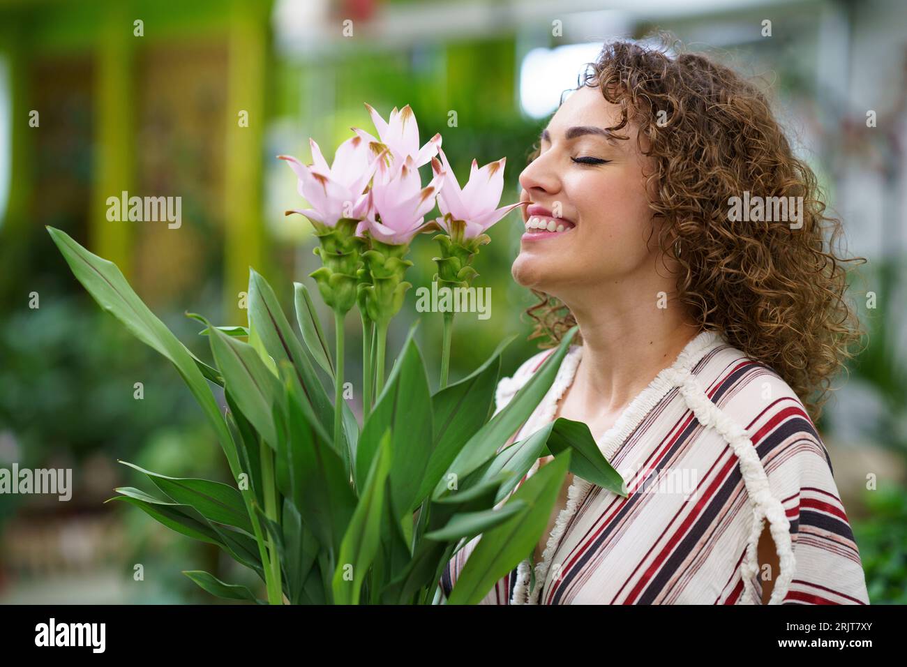 Happy woman with eyes closed smelling flowers at nursery Stock Photo ...