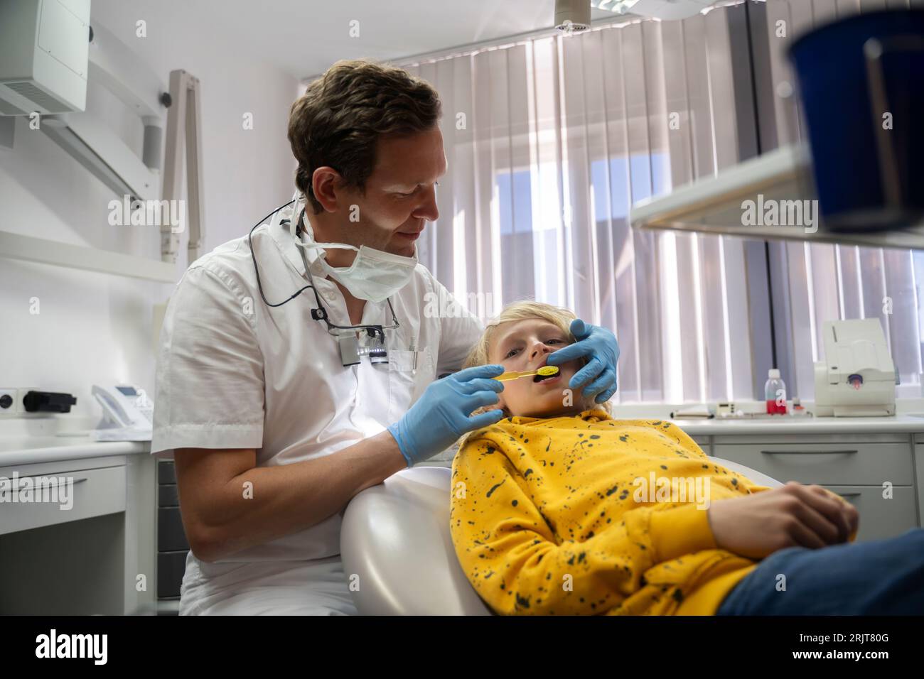 Smiling dentist examining boy's teeth in clinic Stock Photo