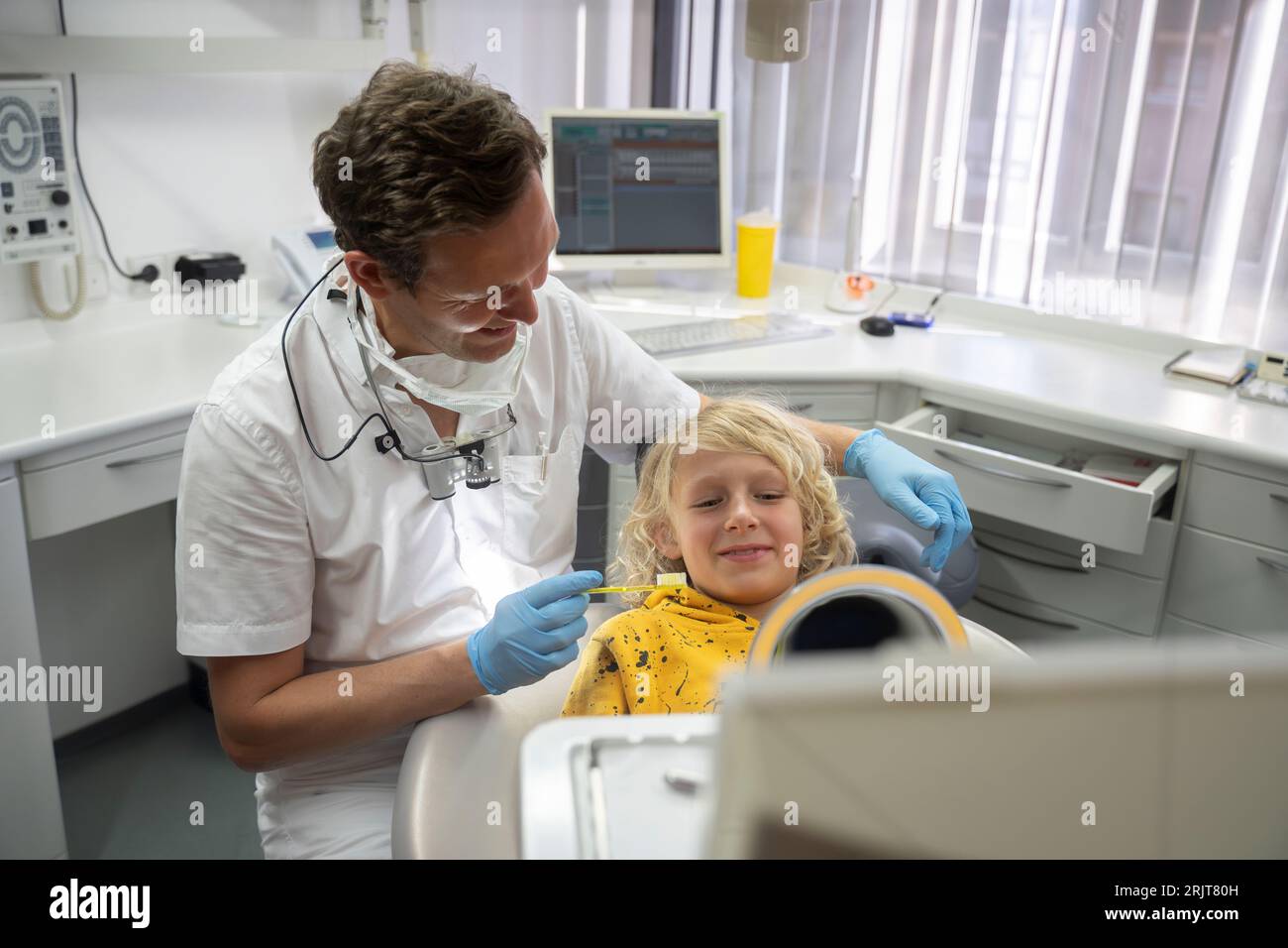 Smiling boy looking in hand mirror at dental clinic Stock Photo