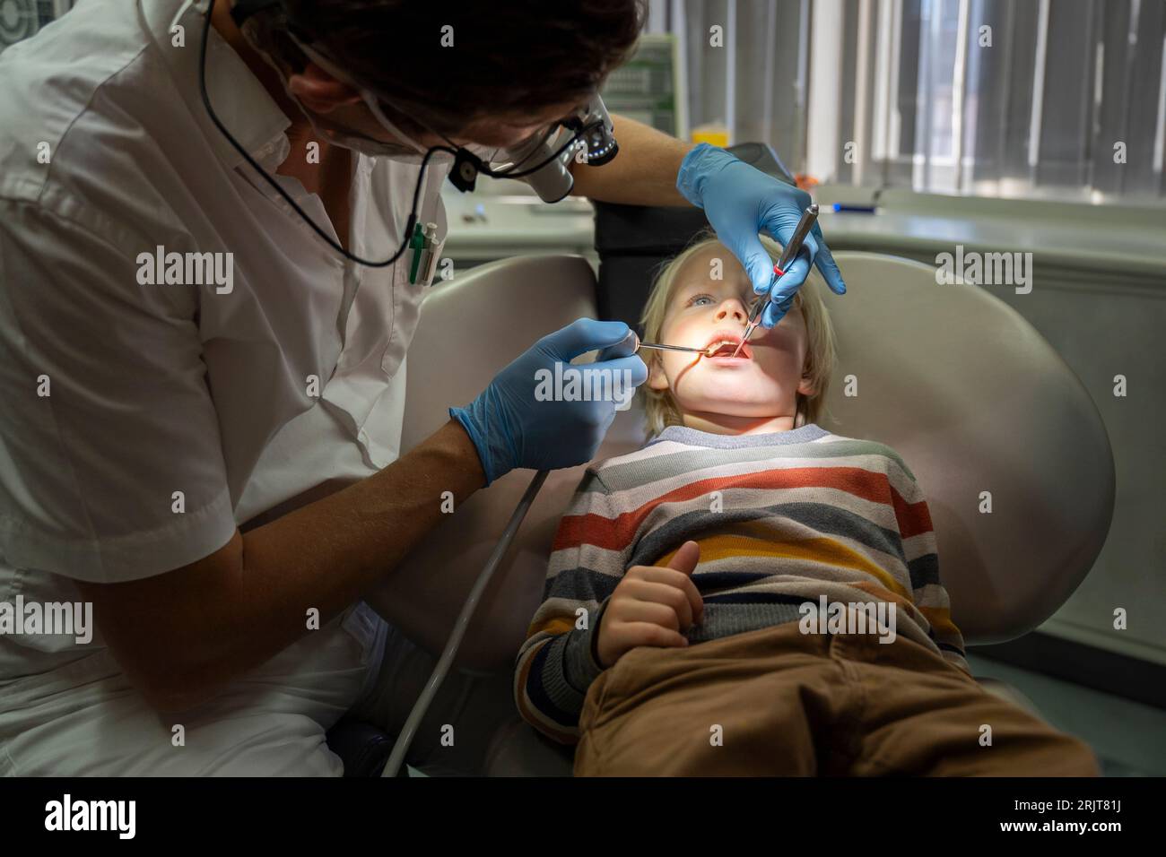 Dentist examining patient's teeth with dental equipment at clinic Stock Photo