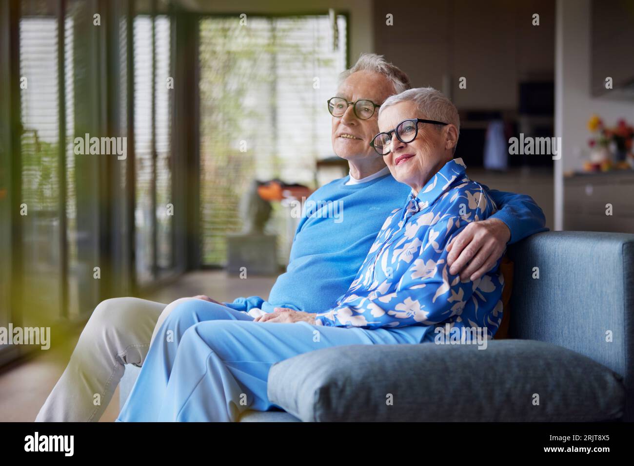 Senior man embracing woman on couch at home Stock Photo