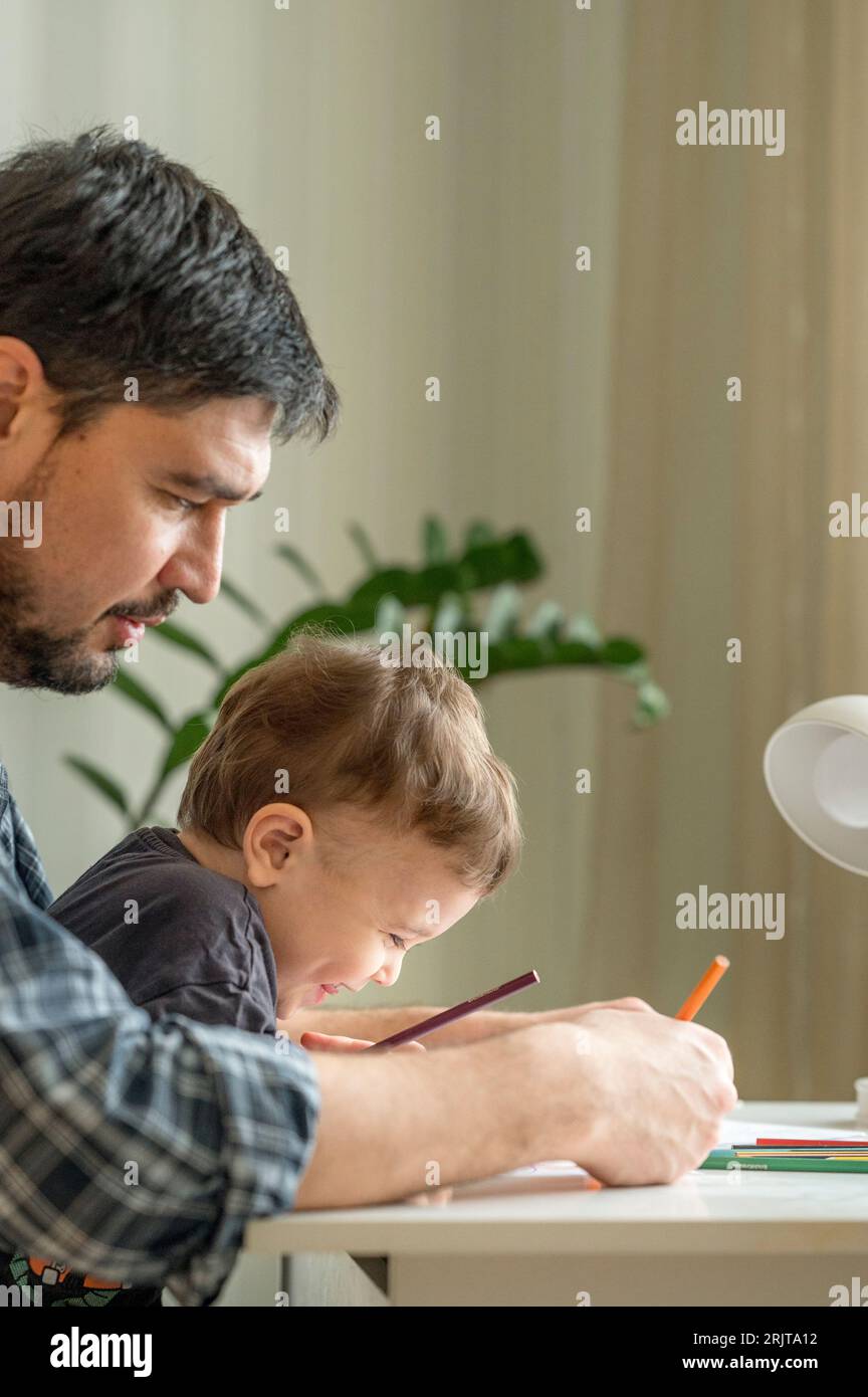 Father and son spending leisure time doing coloring at home Stock Photo