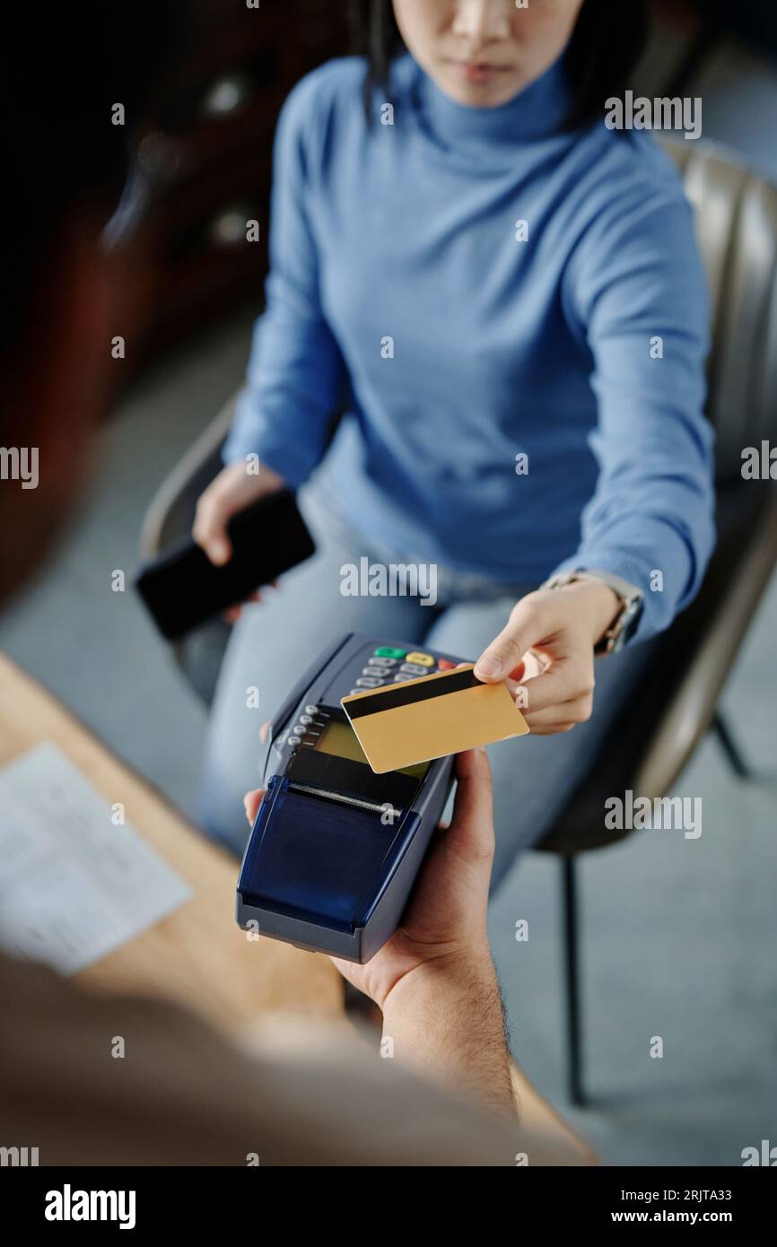 Woman making payment through credit card on machine in cafe Stock Photo