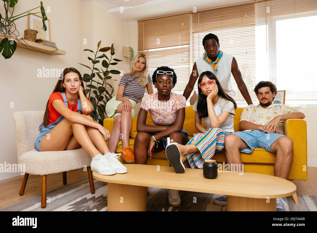 Multi-ethnic friends sitting on sofa at home Stock Photo