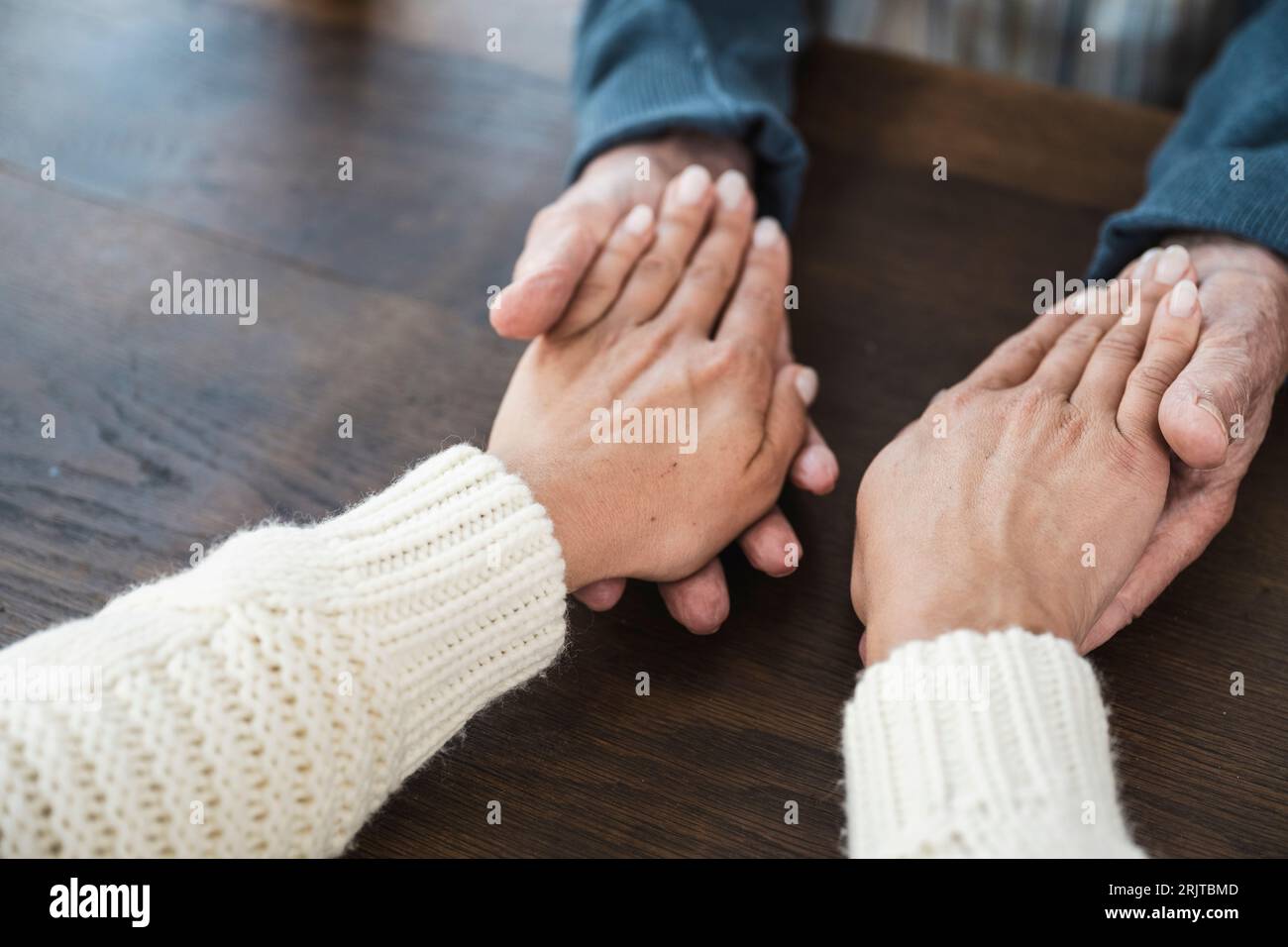 Senior man holding hands of daughter at table Stock Photo