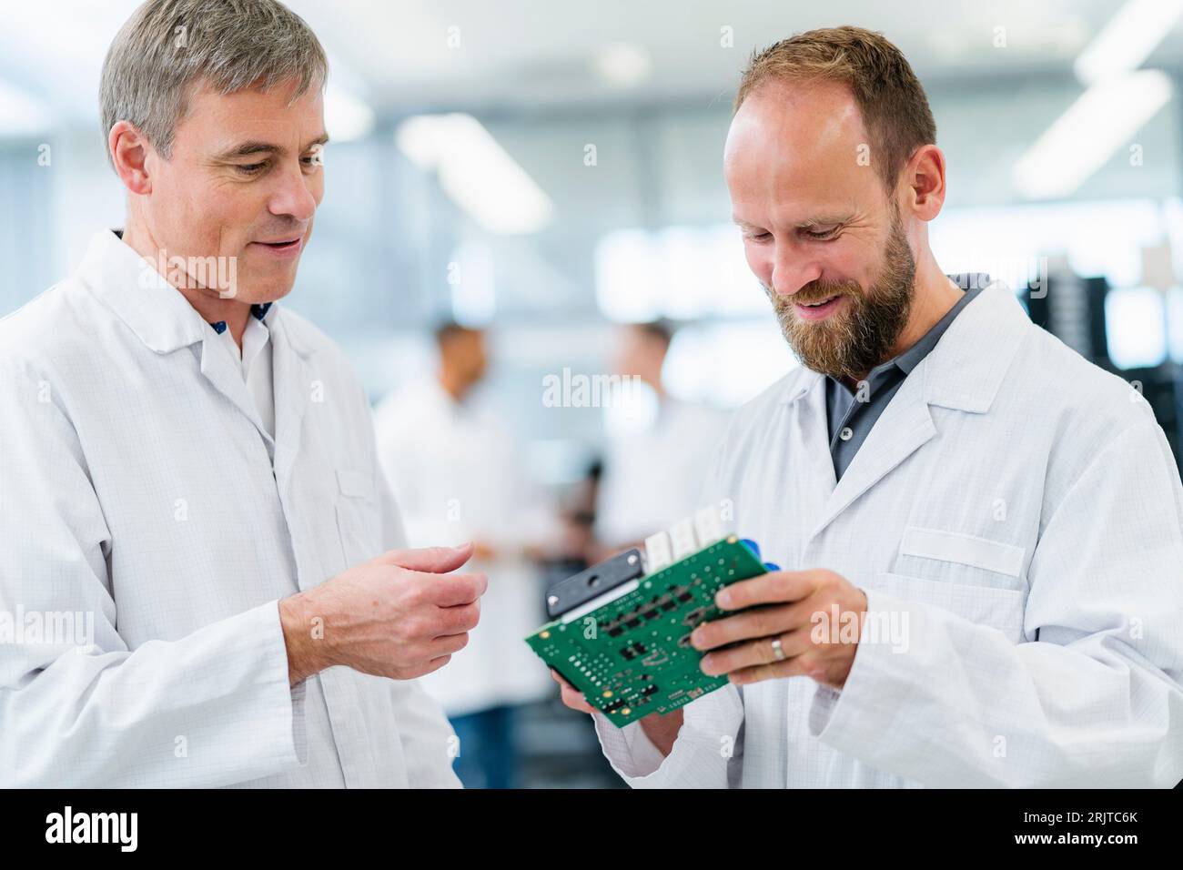 Deutschland, M51, M45, M31, M28, Elektronikfertigung in einem Unternehmen, Besprechung Mitarbeiter in weißen Kitteln mit Plantine Stock Photo